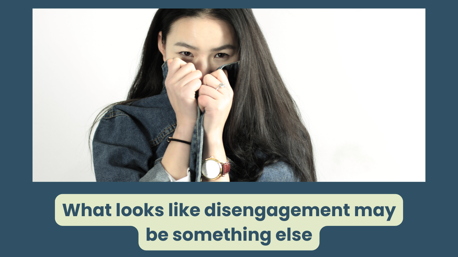 A women with dark hair covers her face with her jacket - she is a bit shy it would appear