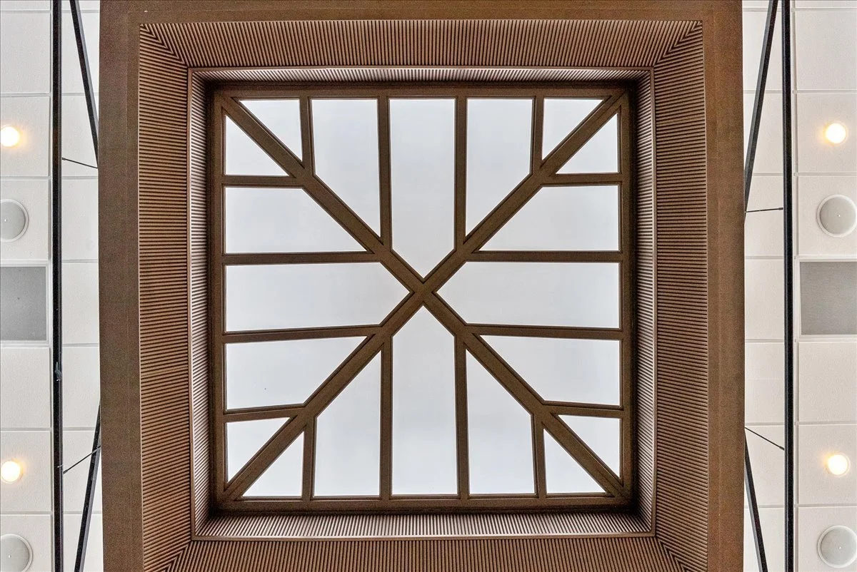 Ceiling with wooden framework and glass panels in a building interior.