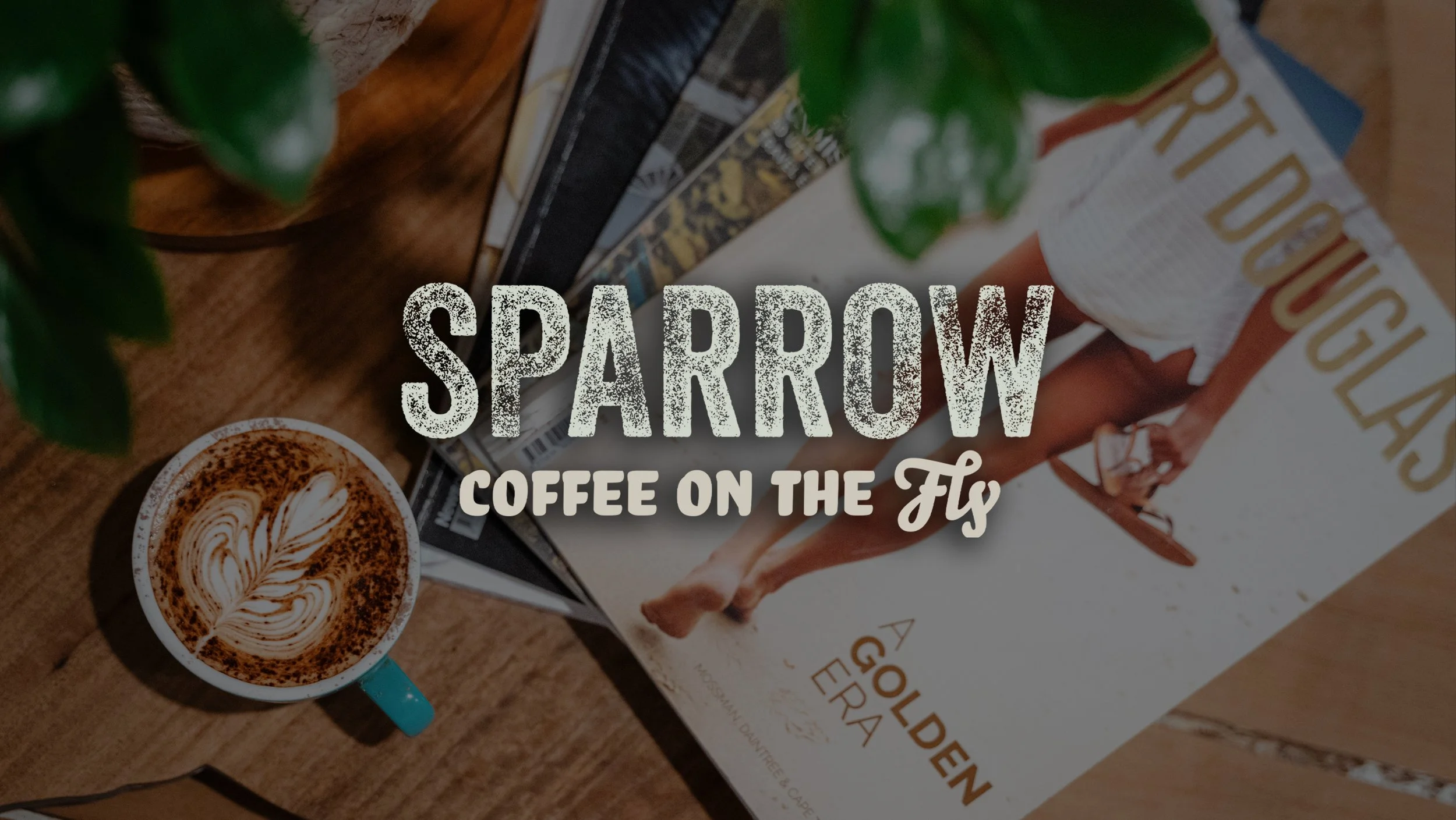 A top-down view of a coffee cup with latte art, a green plant, a magazine page, and a book titled 'A Godfather's Espresso'. Overlaid text reads 'SPARROW COFFEE ON THE Fly'.