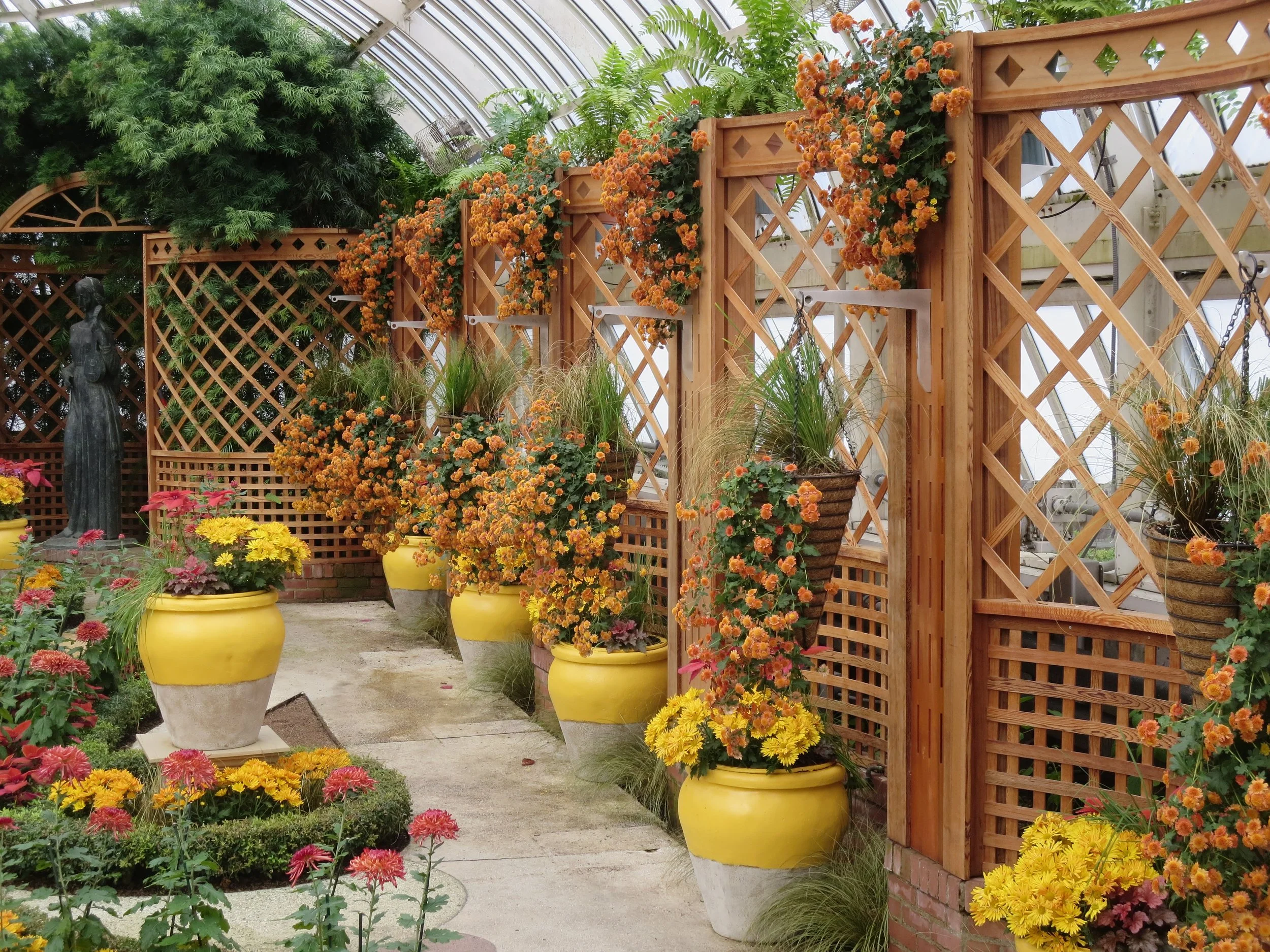 Rust and yellow mums in brown baskets and in yellow and white urns