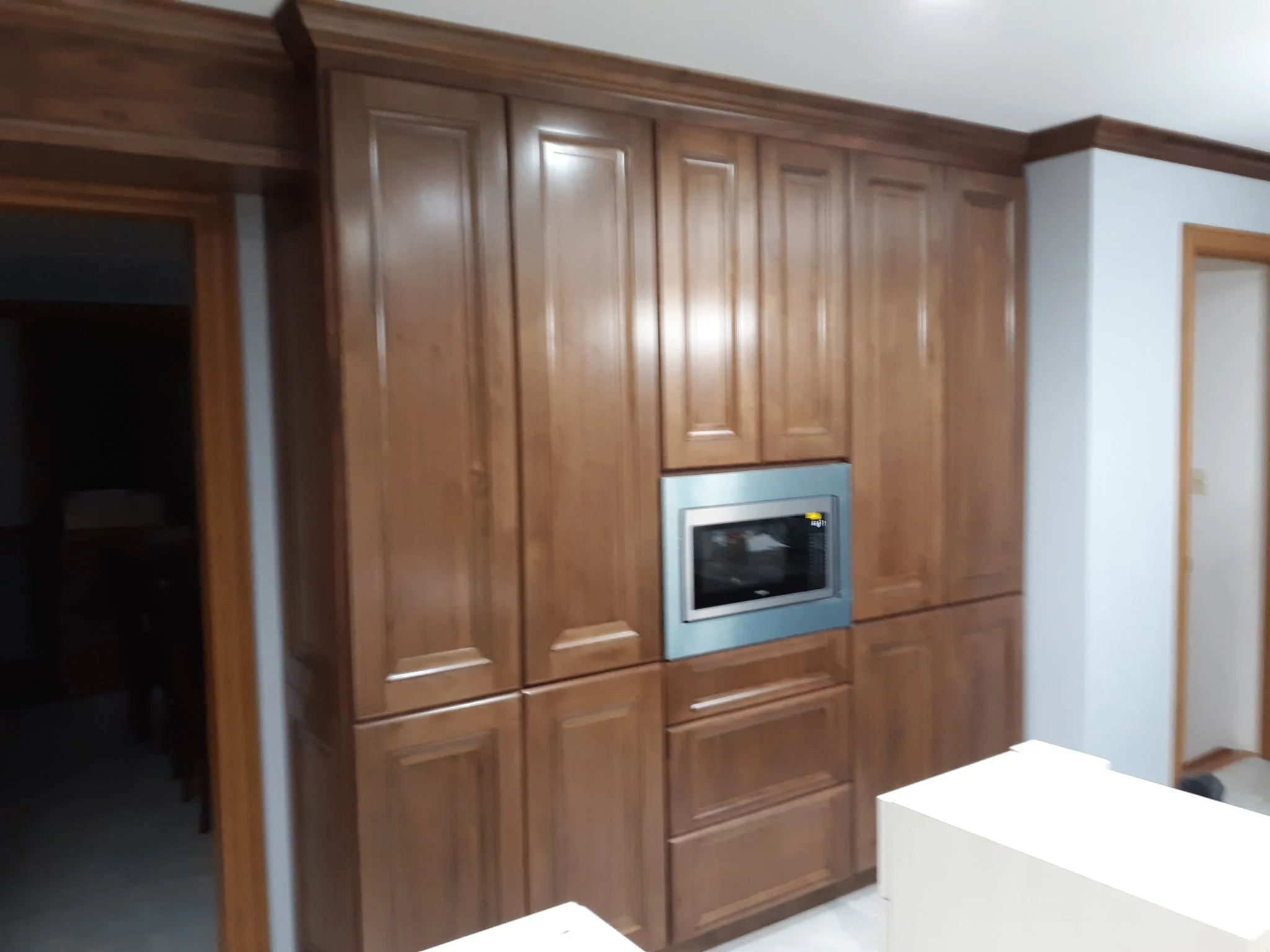 Kitchen with wooden cabinets and built-in microwave, white walls, and doorways.