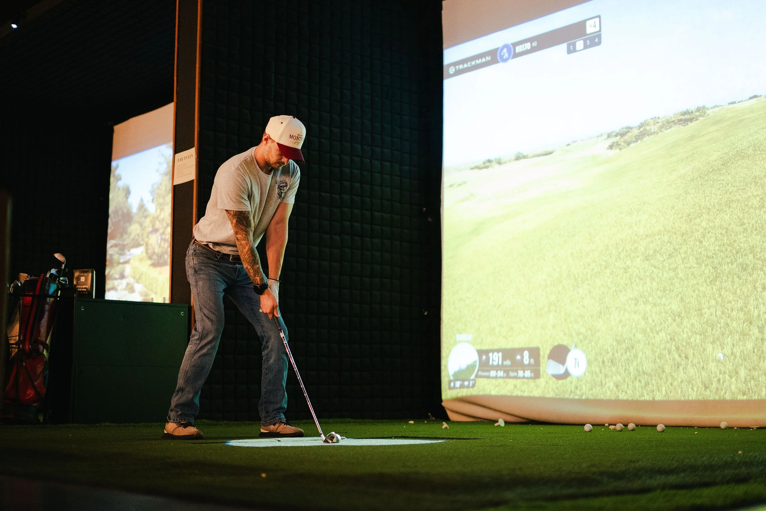 Man practicing golf swing indoors in front of a large screen