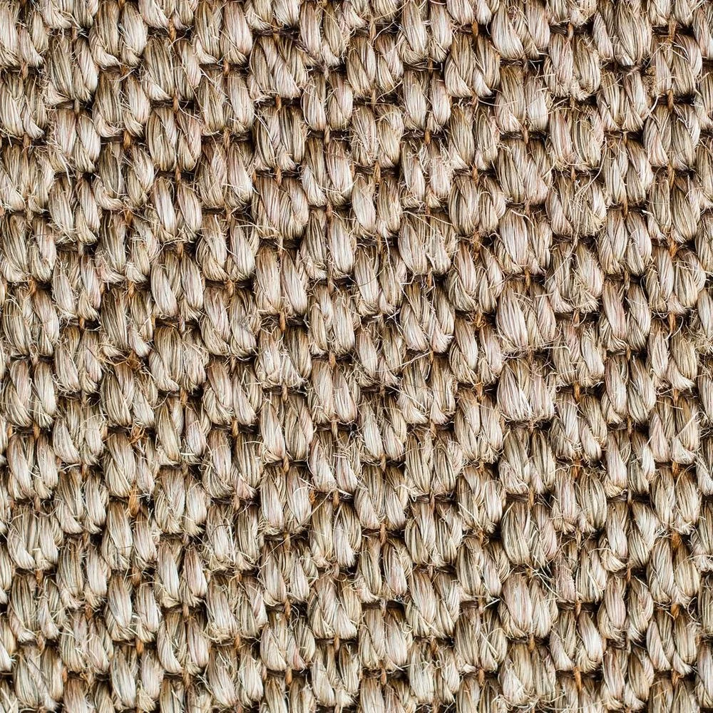 Close-up of a glass coffee table with a glass object on top, placed on a textured woven rug.