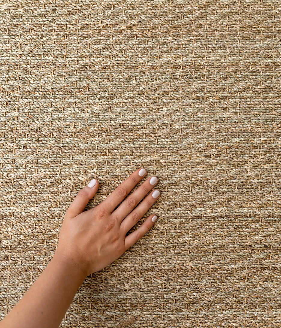 Close-up of a textured beige seagrass with a curved wooden panel in the background.