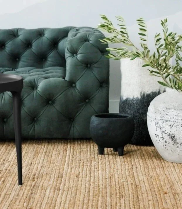 Skateboards hanging on brick walls, with a skateboard leaning against the wall on the left, and a seating area with benches and magazines in a room with brick walls and large windows.