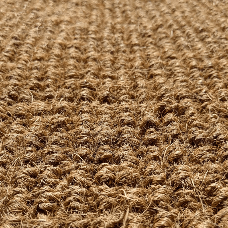 Close-up of a textured, brown, coir, woven fabric or carpet with a pattern of tightly twisted fibers.