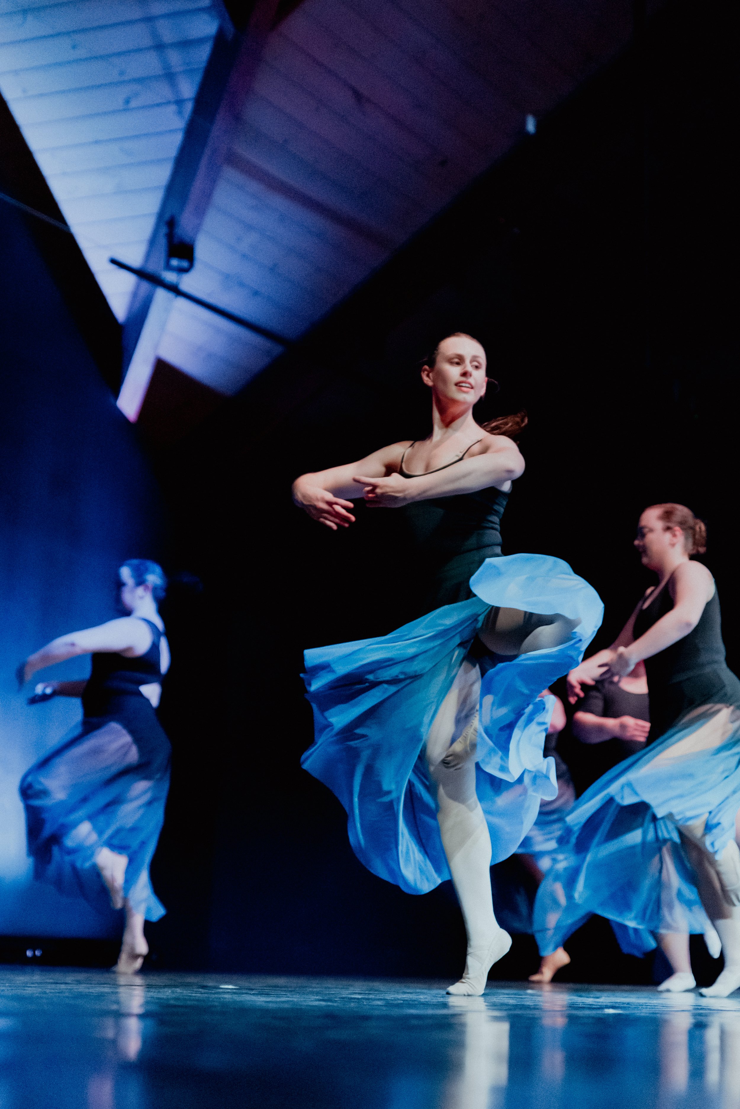 Black and white photo of ballet dancers performing on stage. The central dancer is in a tutu and pointe shoes, with others performing in the background. The backdrop suggests a whimsical setting with large candy decorations.