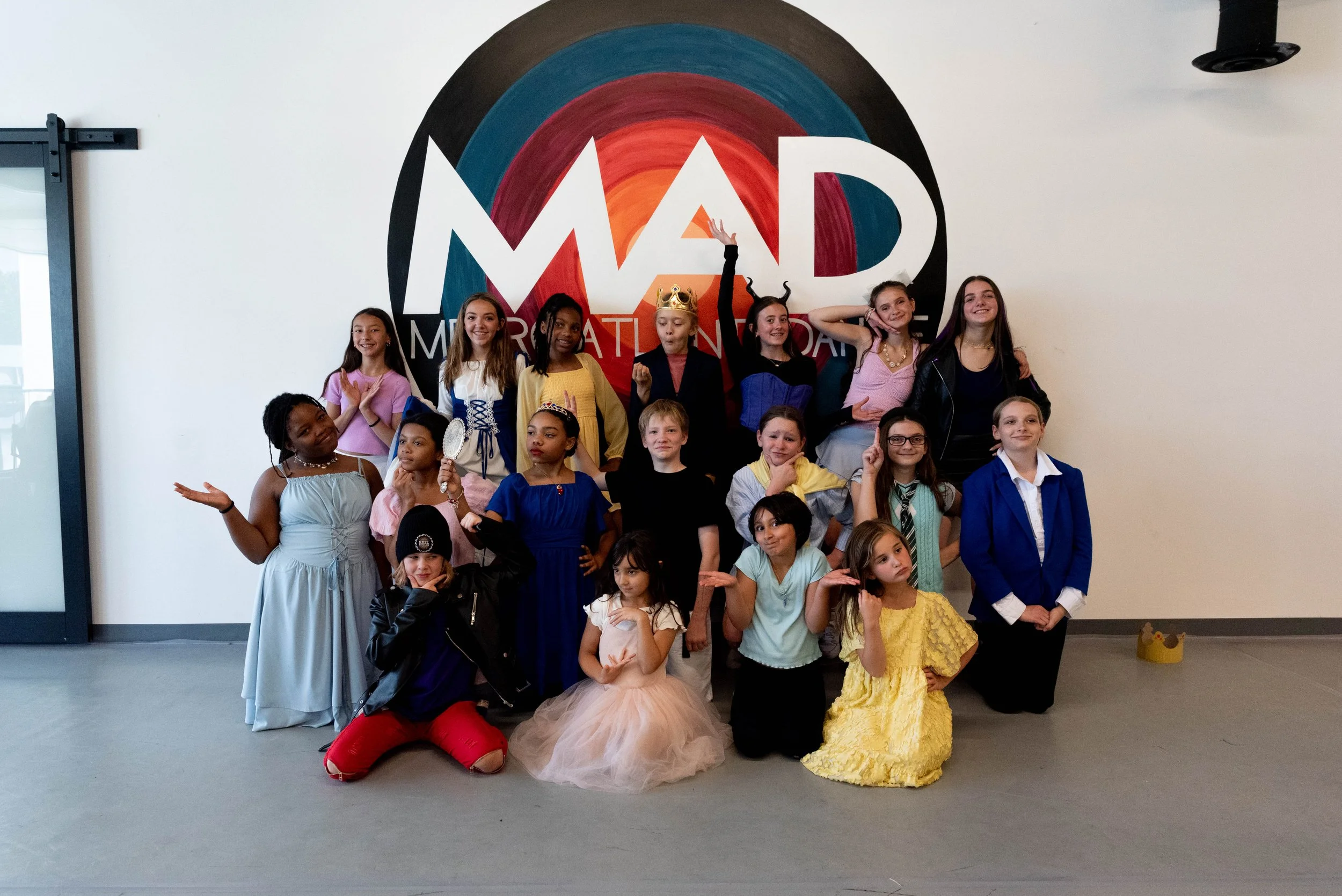Children performing a dance routine in a room with an audience watching.
