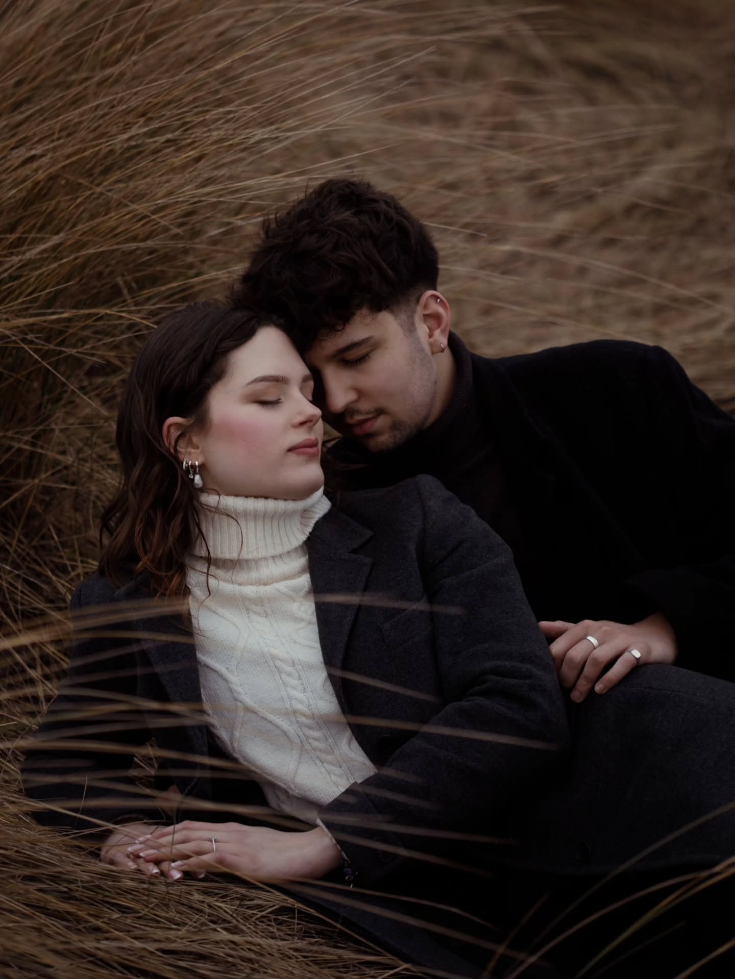 They stand where the tide reaches for the shore, letting the wind pull at their clothes and the salt settle on their skin. Storm clouds gather, heavy and close. The sea rises and falls, restless and sure. 
Amid the elements, they are each other's cal