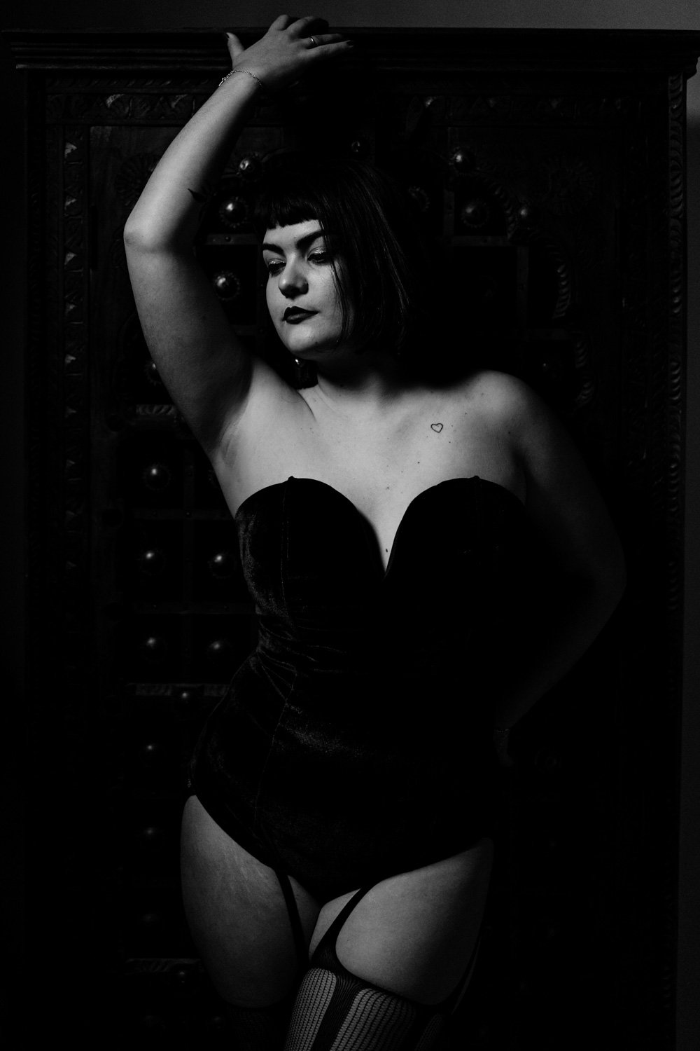 Femme en lingerie pose contre un mur en noir et blanc.