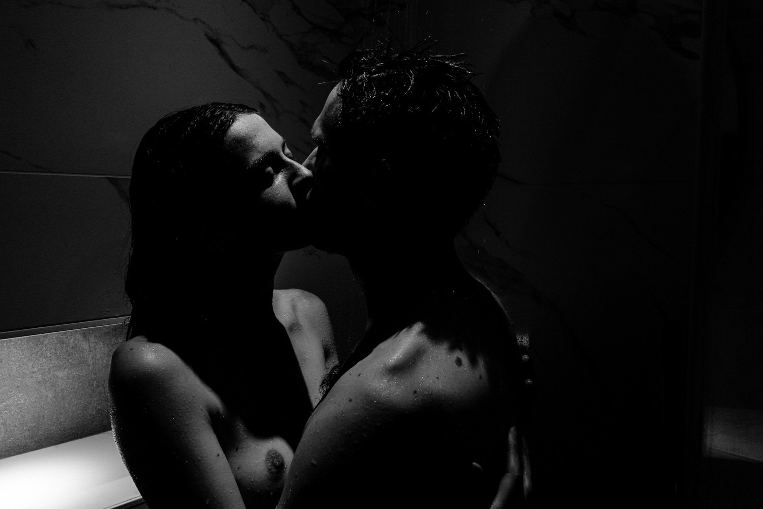 Un couple s'embrassant sous la douche, en noir et blanc.