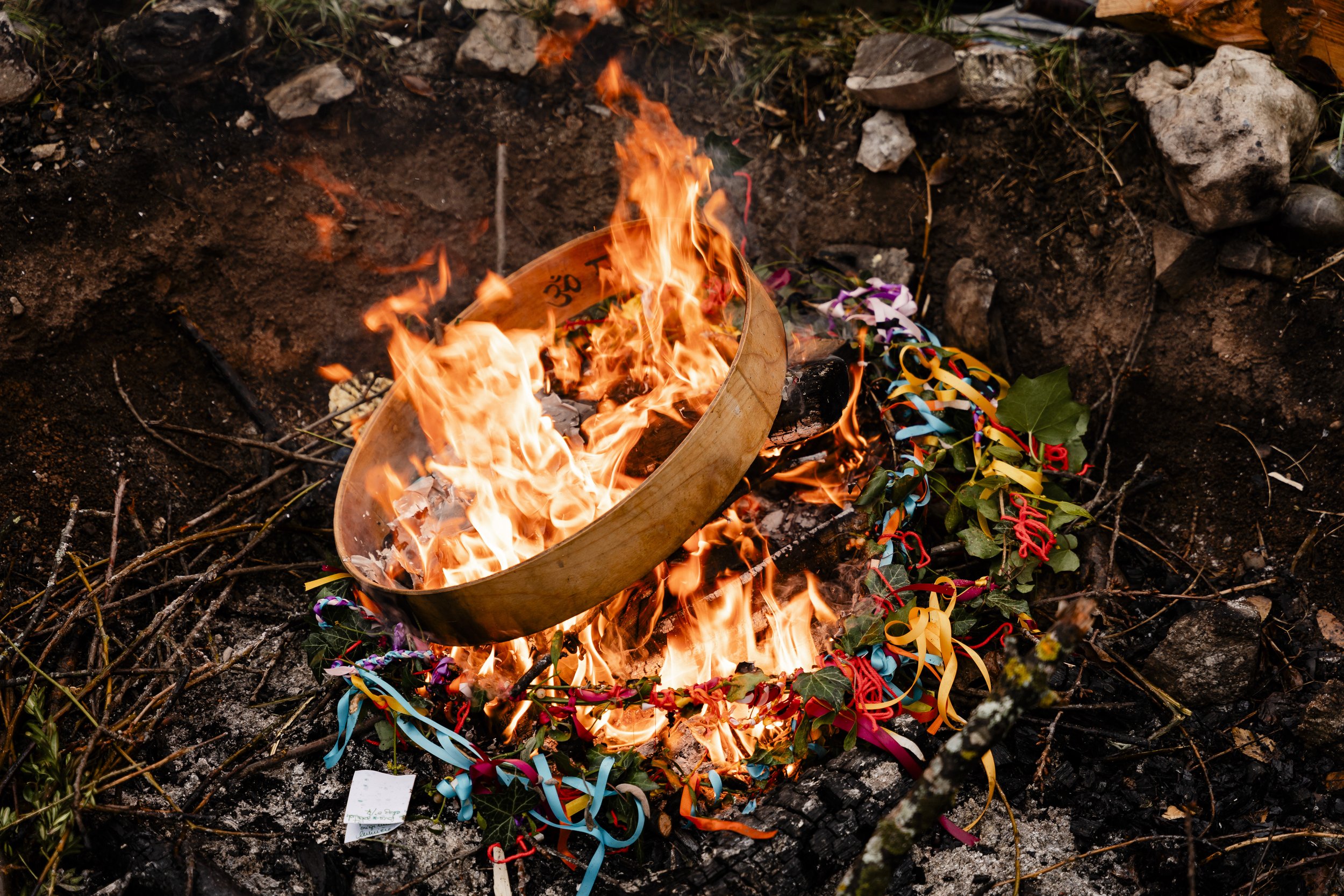 Feu de camp avec des flammes vives brûlant du bois et des objets décorés de rubans colorés.