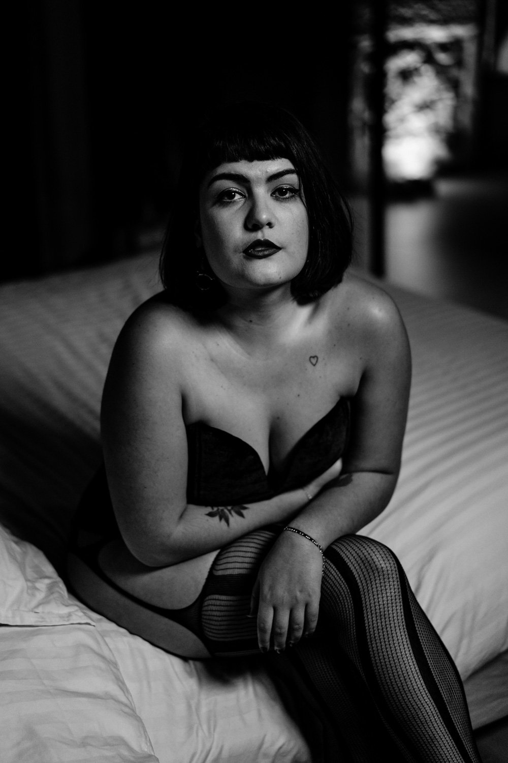 Femme en lingerie assise sur un lit, en noir et blanc.