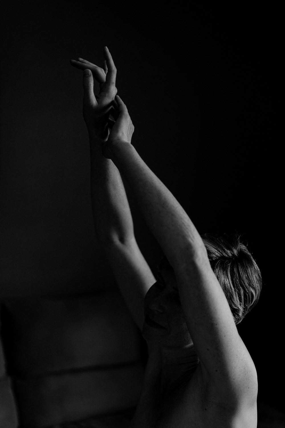 Une personne lève les bras dans une pose gracieuse en noir et blanc.