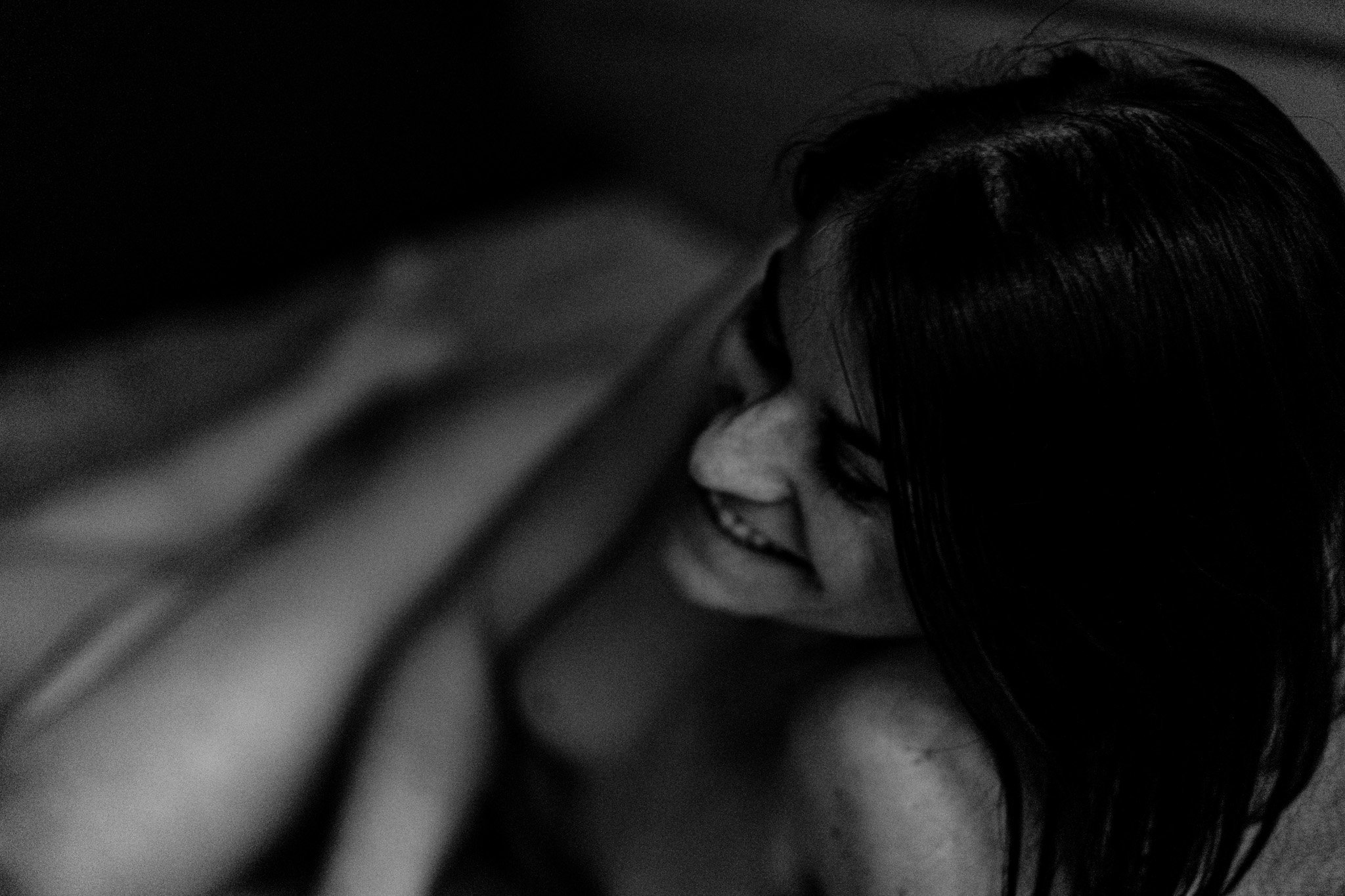 Portrait flou d'une personne souriante allongée, en noir et blanc.