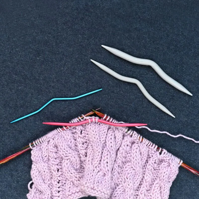KnitPro aluminium cable needles in use with knitting set out on a table.