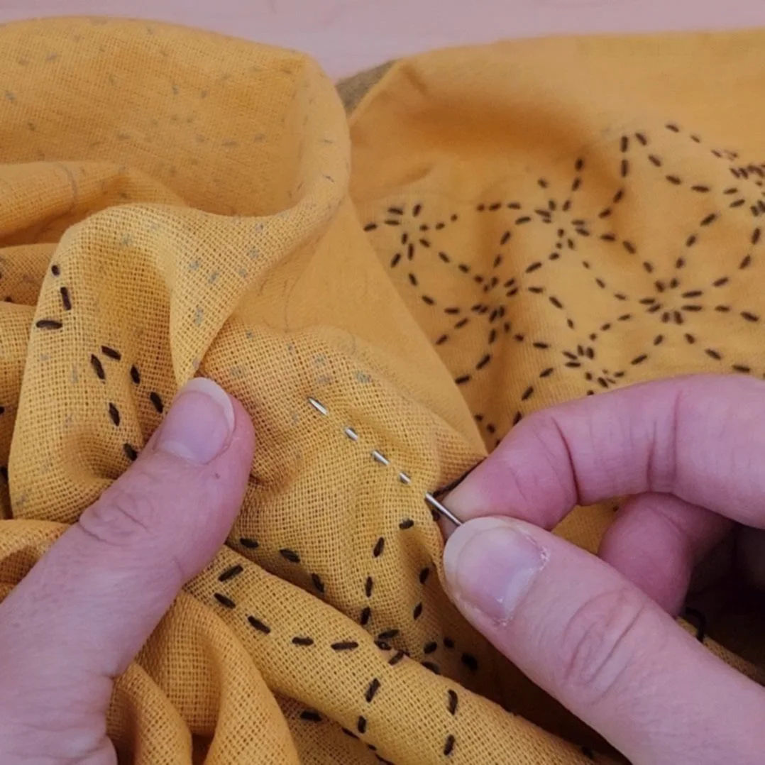 Close-up of fabric with multiple stitches gathered on a sashiko needle.