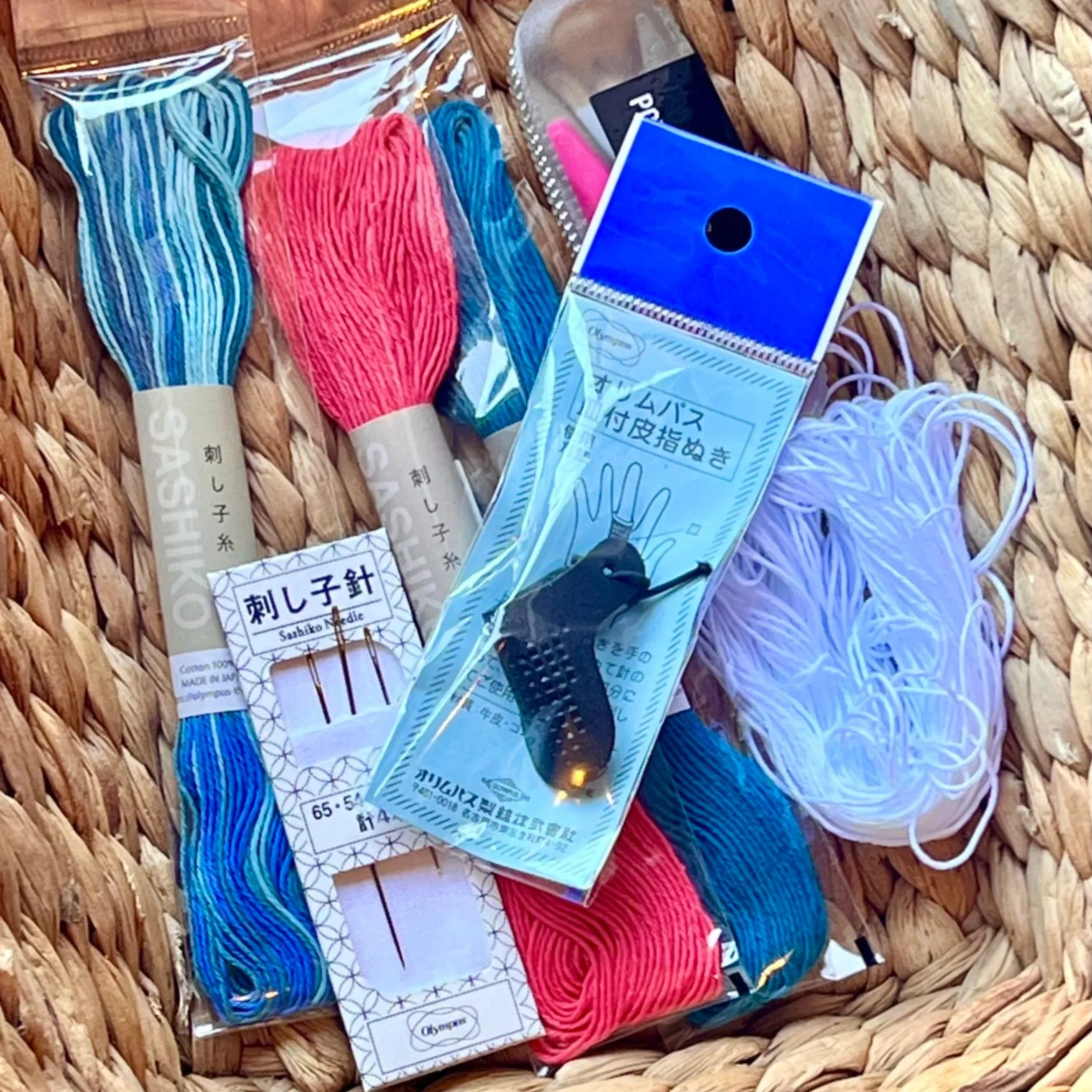 Basket with sashiko threads, needles, and thimble in packaging.