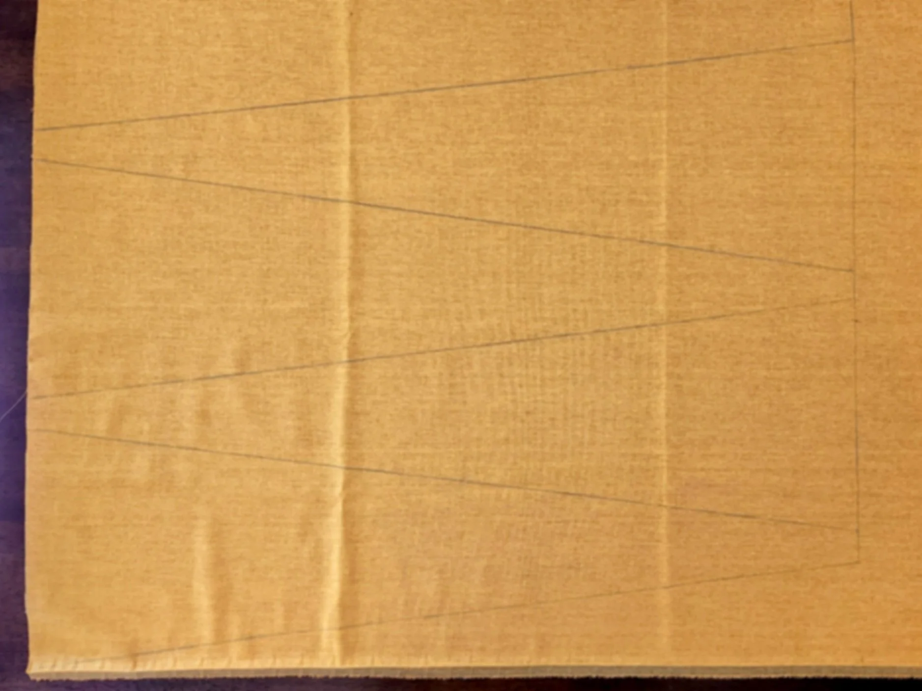 Mustard-coloured linen fabric with isosceles triangle gusset shapes drawn with tailors pencil.