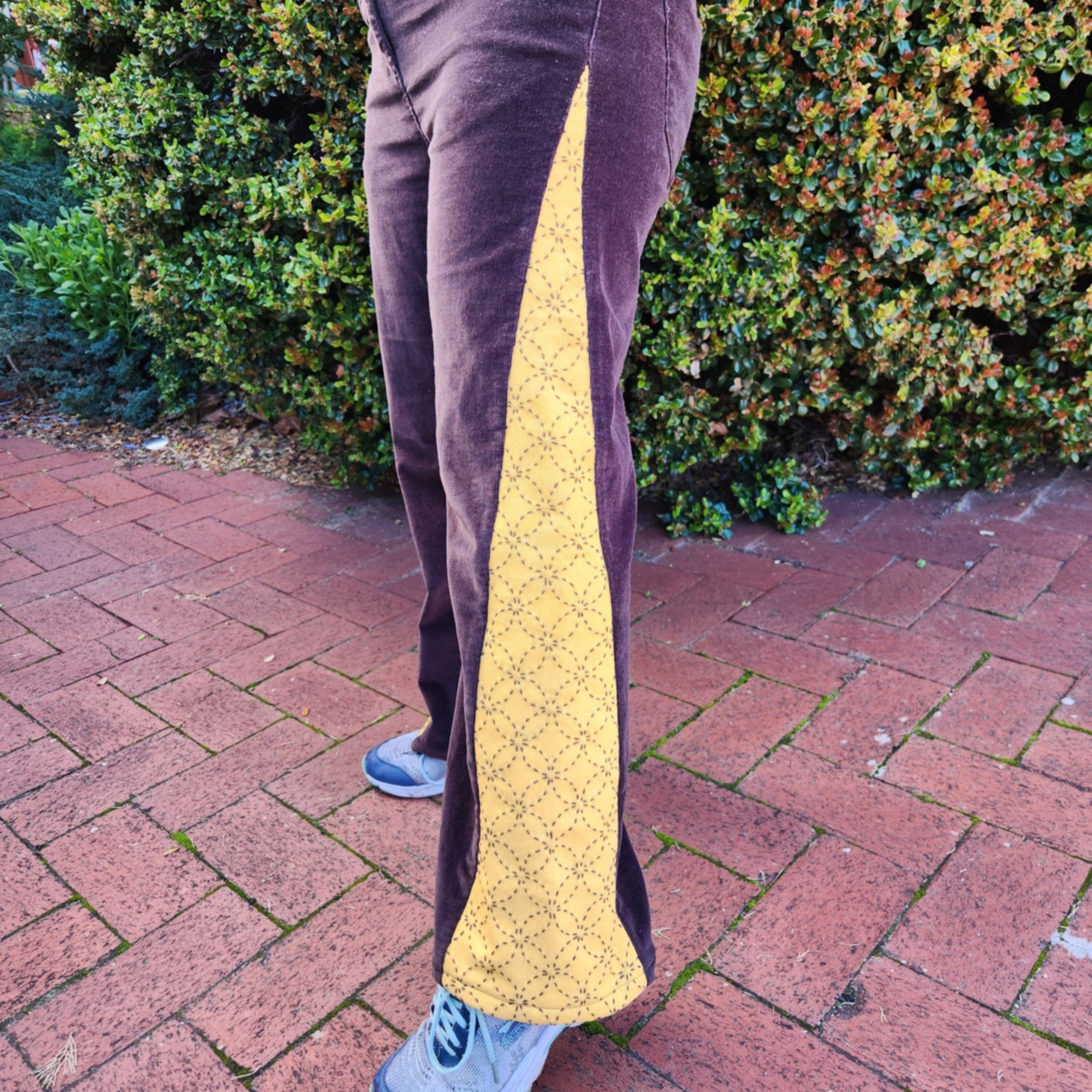 Close-up of mustard linen gusset with brown sashiko stitching on brown corduroy pants showing detailed hand embroidery.