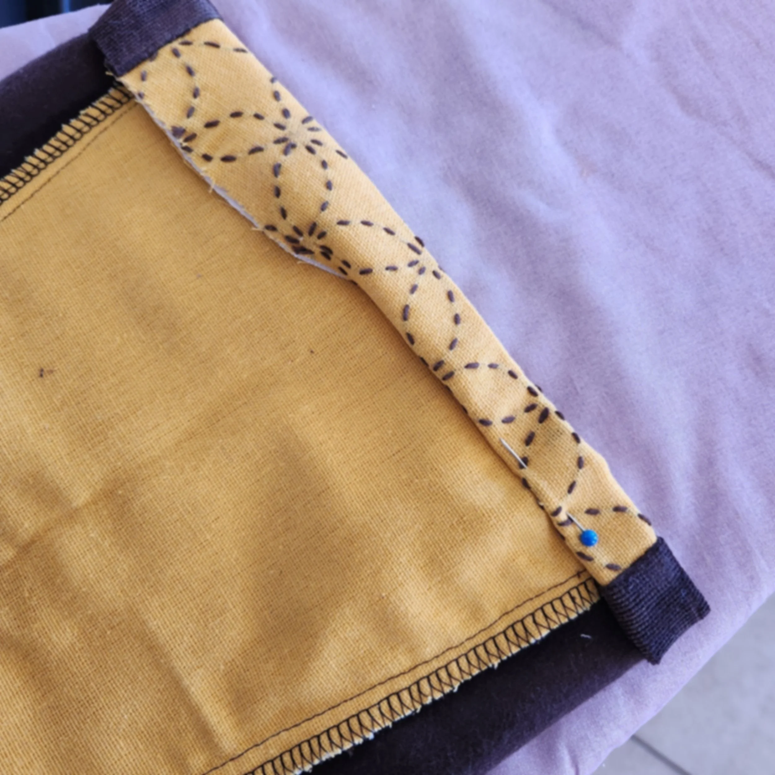 Close-up of brown corduroy pant leg hem folded and pinned in place before ironing and sewing.