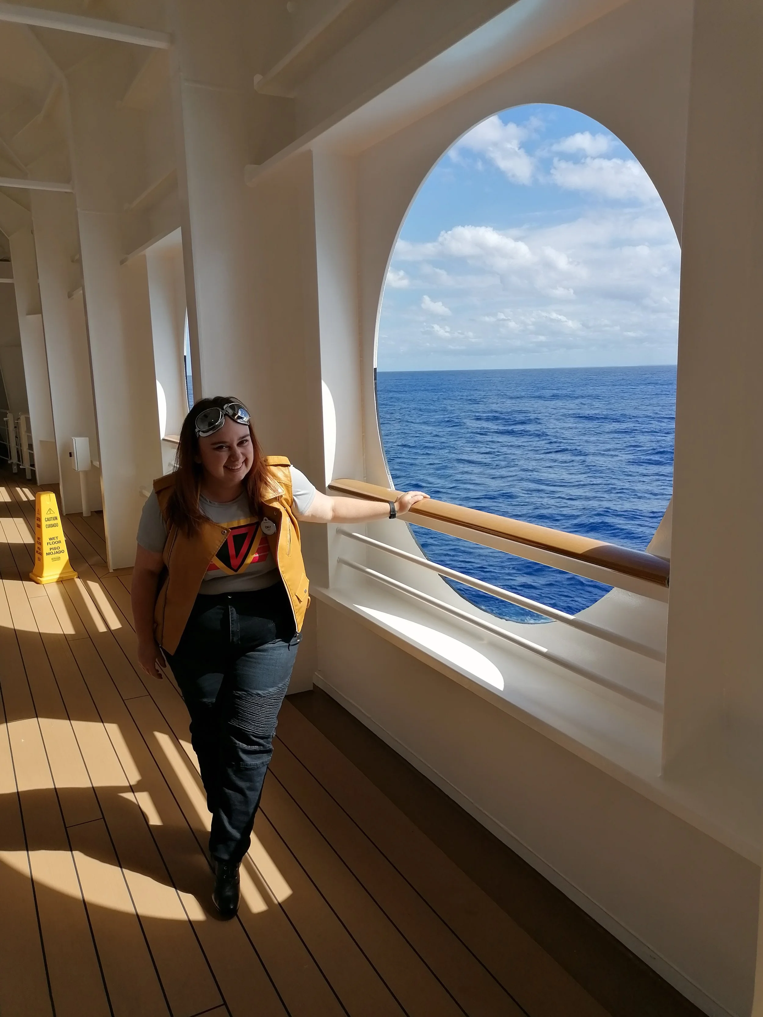Emily Stangroom standing by the porthole on the Disney Fantasy enjoying the view