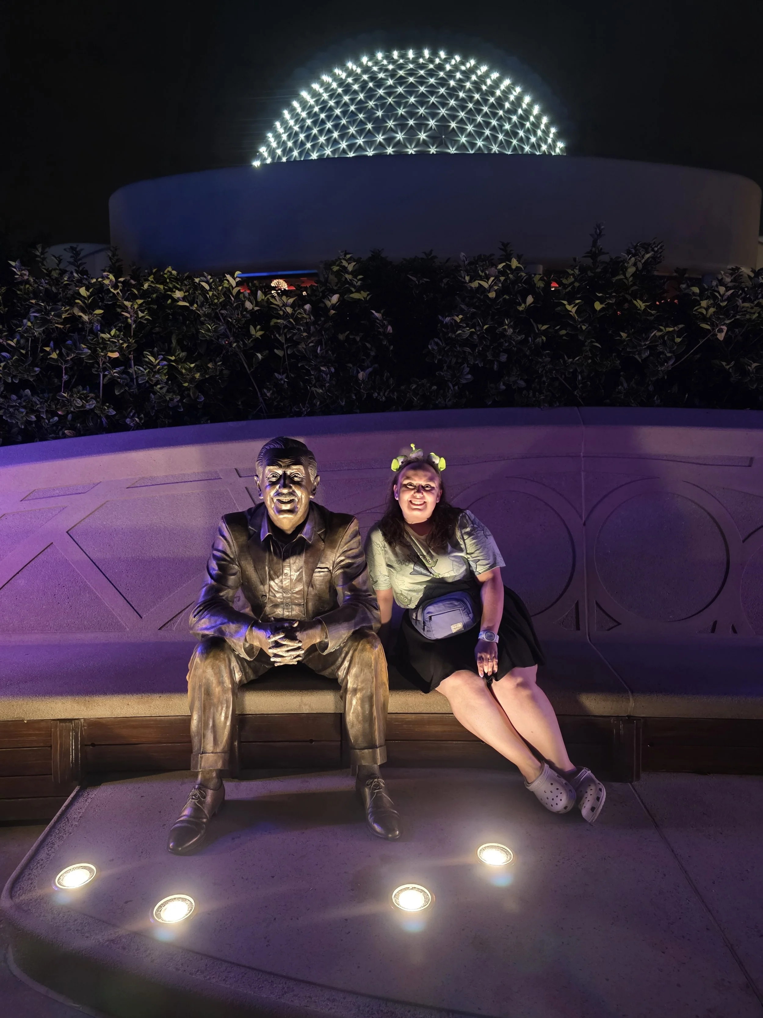 Emily sitting next to Walt's statue at Epcot