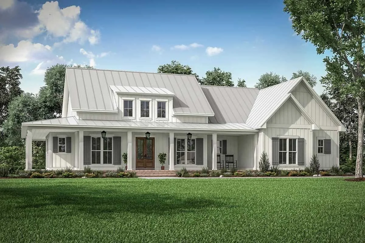 A white, farmhouse-style house with a metal roof, multiple windows, front porch, and a well-manicured lawn.