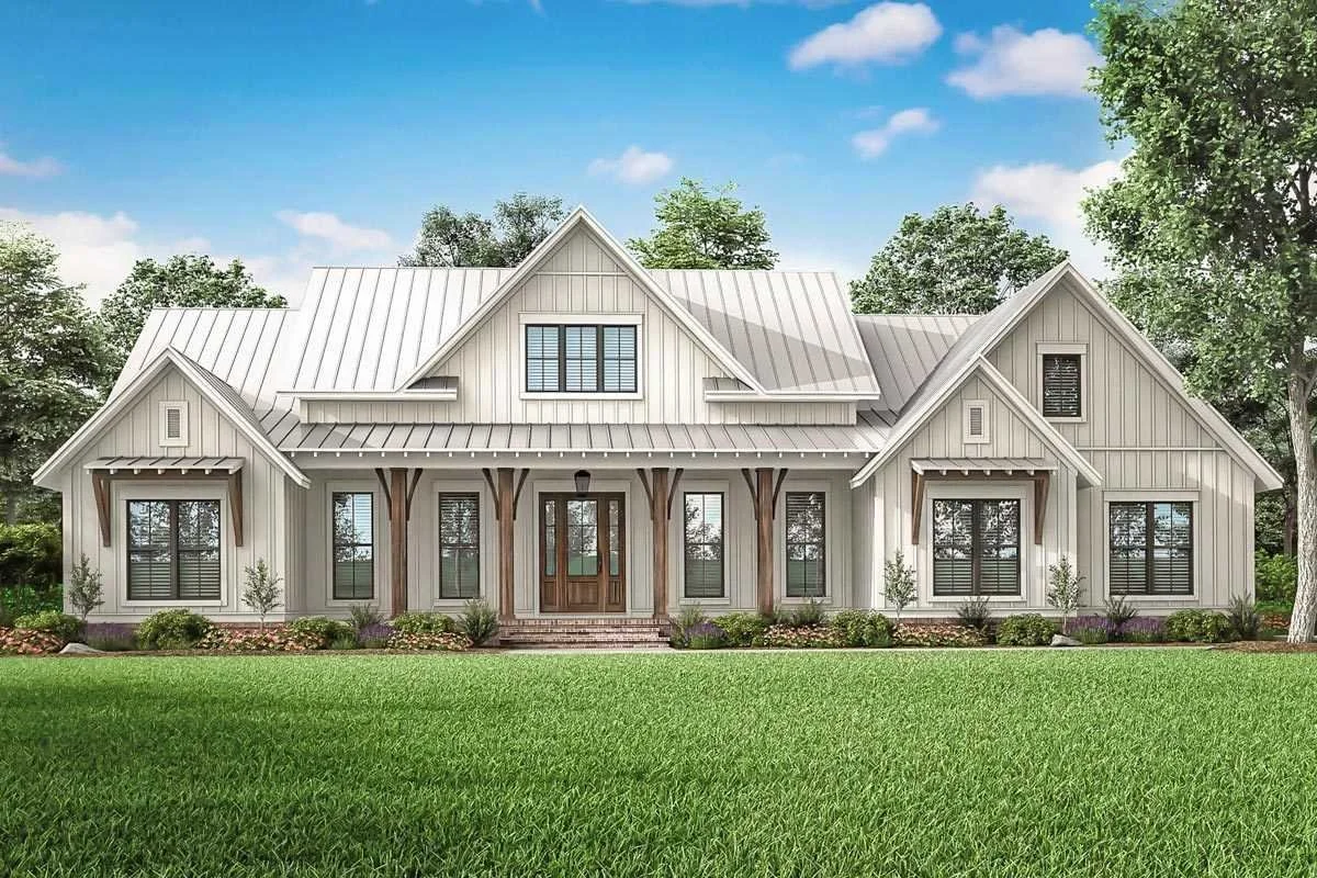 A modern farmhouse-style house with a metal roof and white siding, surrounded by a green lawn and trees.