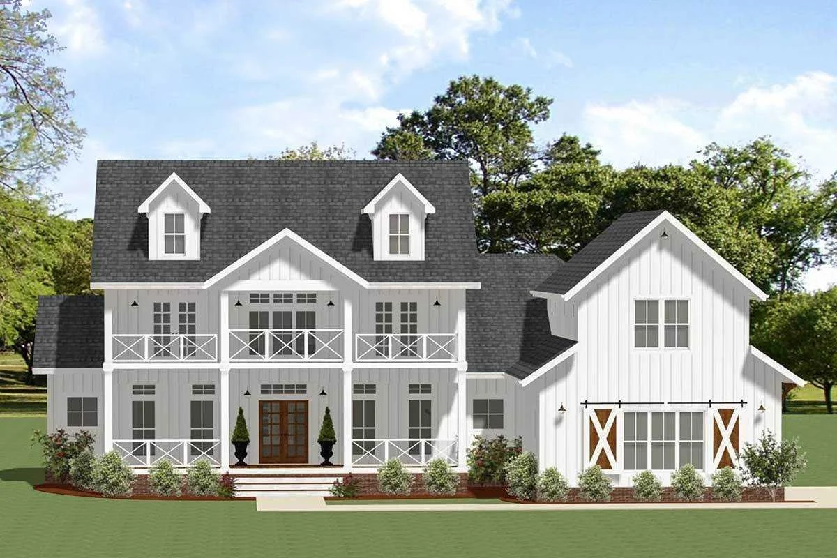 A two-story white house with black roof shingles, multiple windows, a front porch with stairs, and landscaping with bushes and trees.