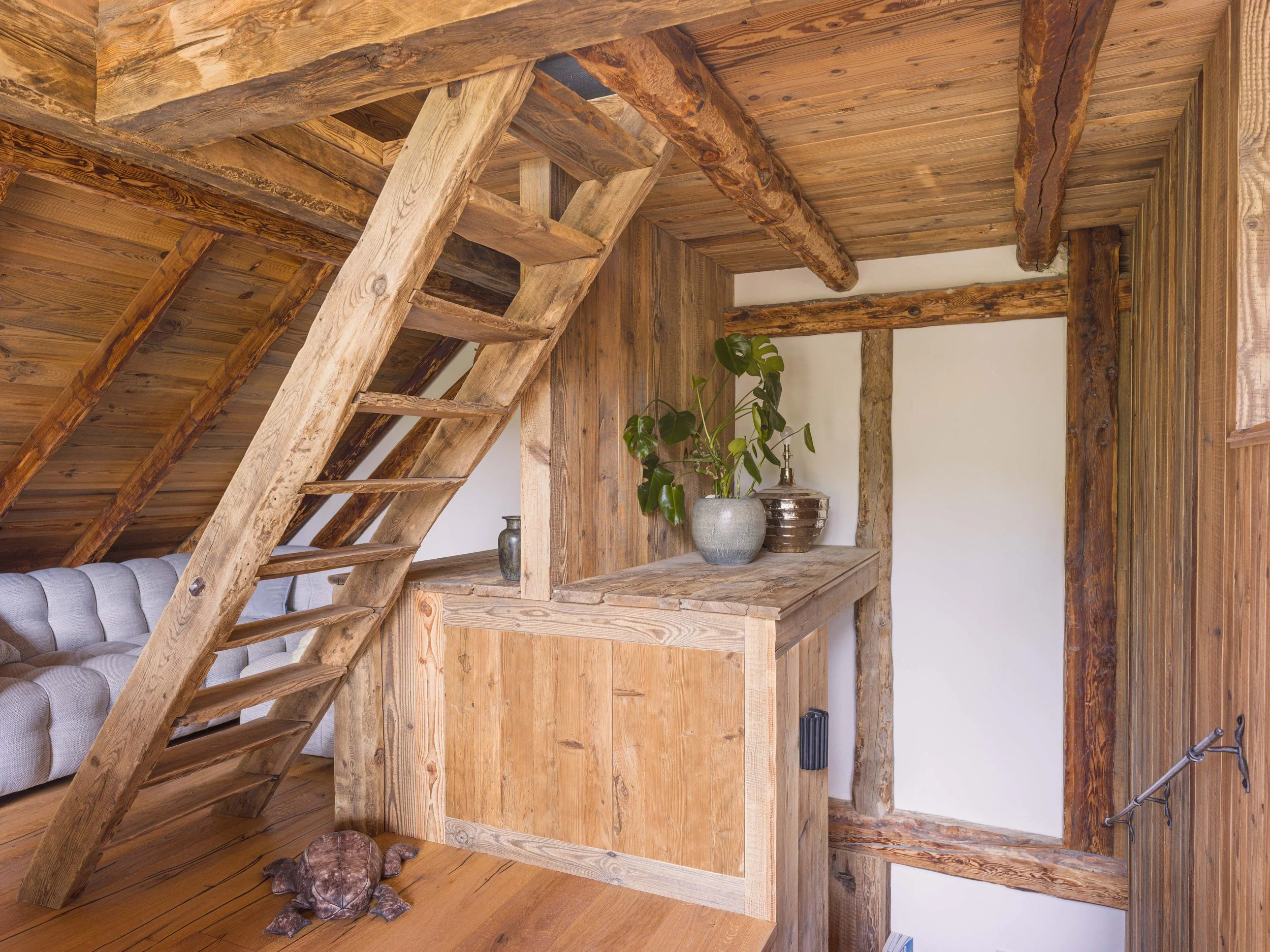 Un escalier en bois avec des rondins et une petite niche agrémentée de plantes en pot et de vases.
