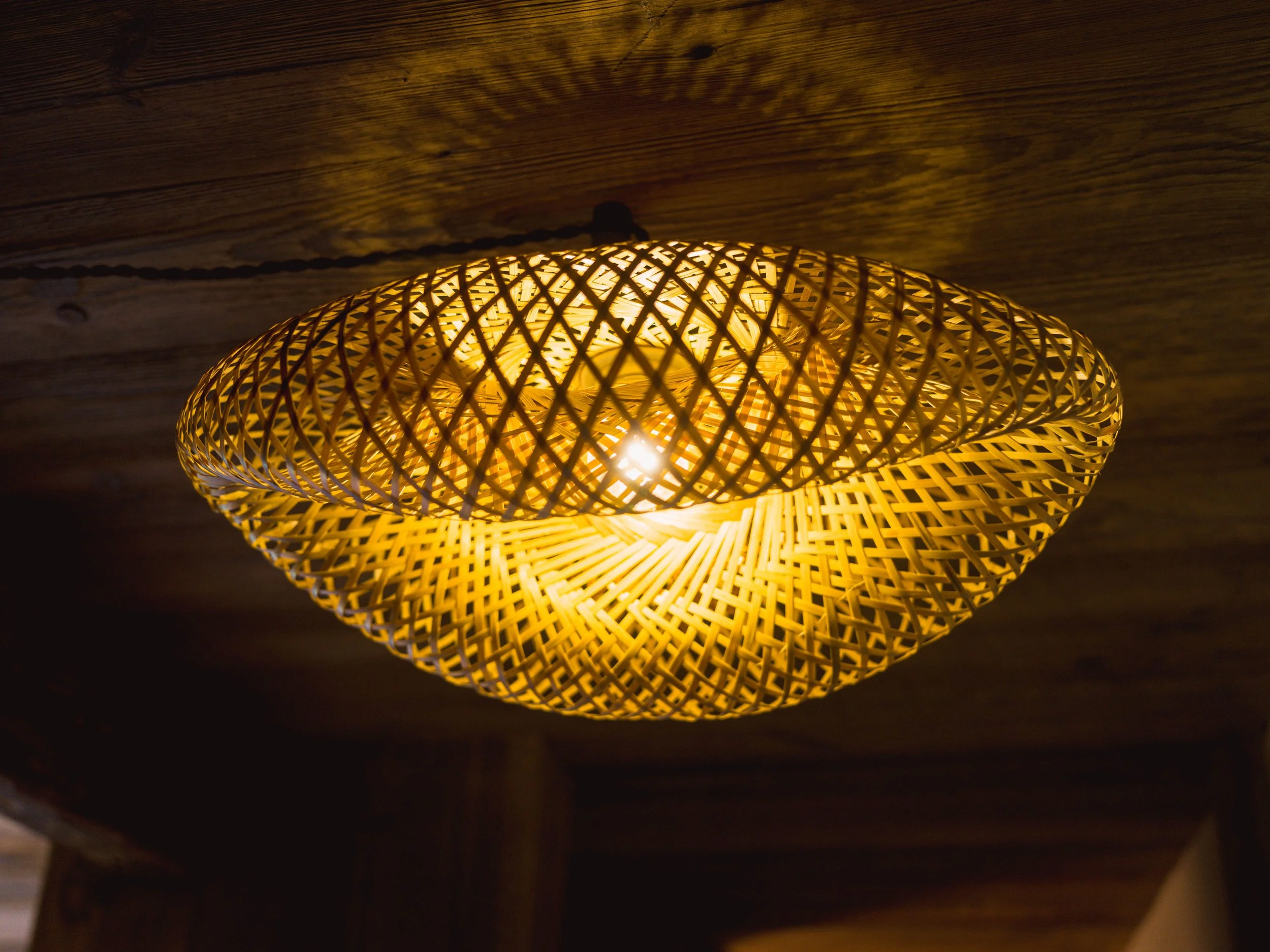 Une lanterne suspendue en tissu, de couleur brun jaunâtre, diffusait une lumière chaleureuse qui illuminait le plafond en bois au-dessus.