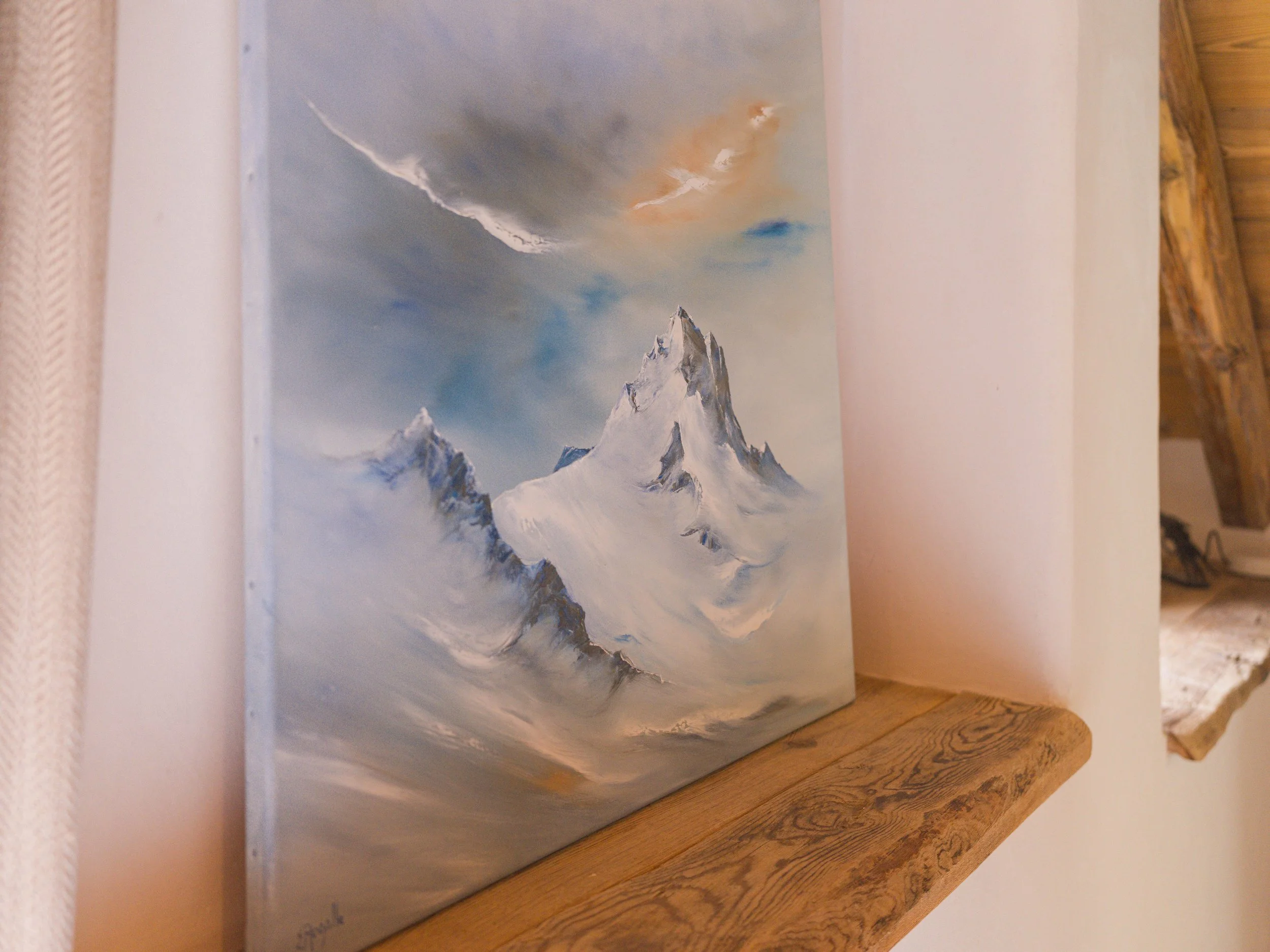 Une peinture représentant un paysage de montagne avec un sommet enneigé et un ciel coloré parsemé de nuages.
