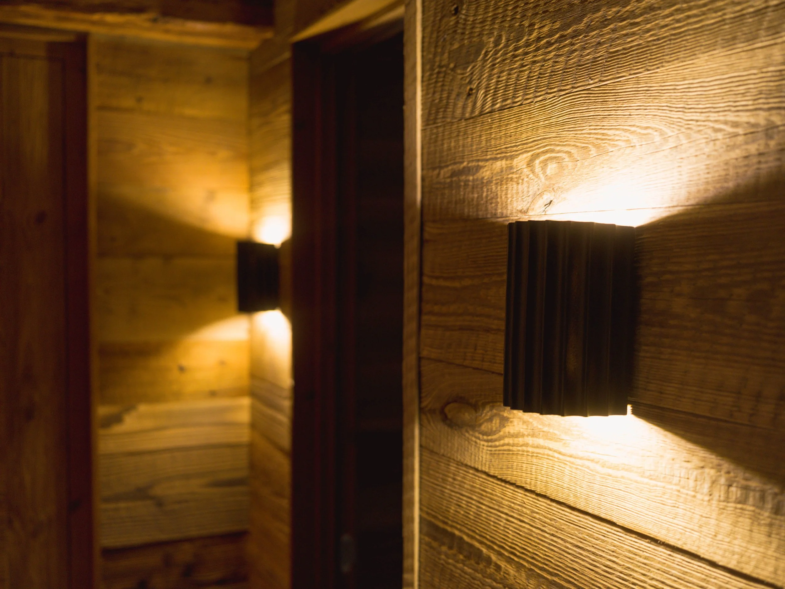 Intérieur en bois faiblement éclairé, avec des planches horizontales sur les murs, sous un éclairage chaleureux.