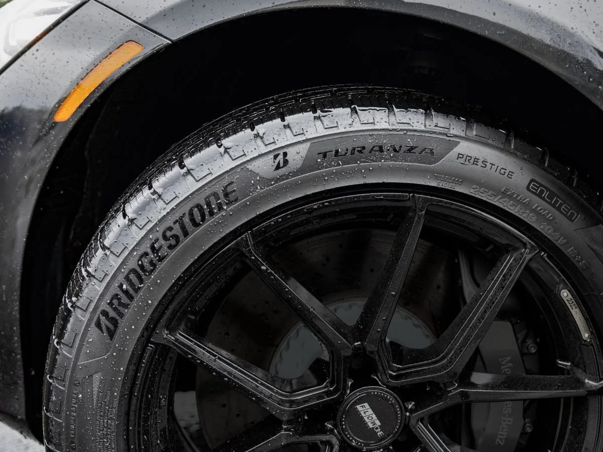 Bridgestone Turanza Prestige all-season tire with water droplets on a black multi-spoke wheel.