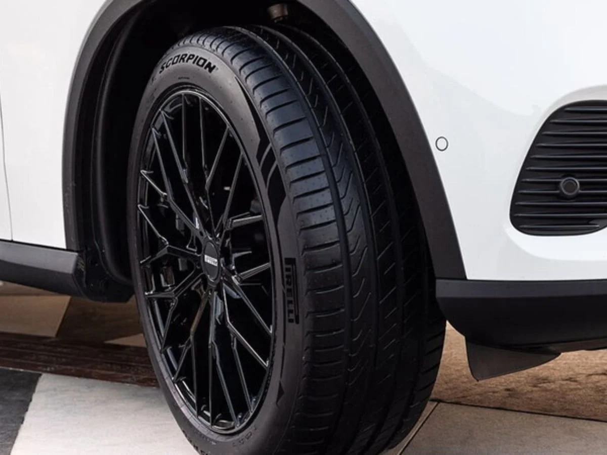 Pirelli Scorpion tire on a black multi-spoke wheel of a white SUV, showing all-season tread detail.