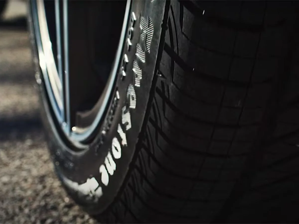 Close-up of a Firestone tire with raised white lettering on the sidewall and visible tread depth.
