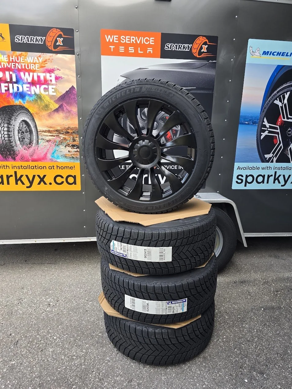 Sparky X Tesla winter wheel package featuring Michelin X-Ice Snow tires mounted on matte black turbine rims.