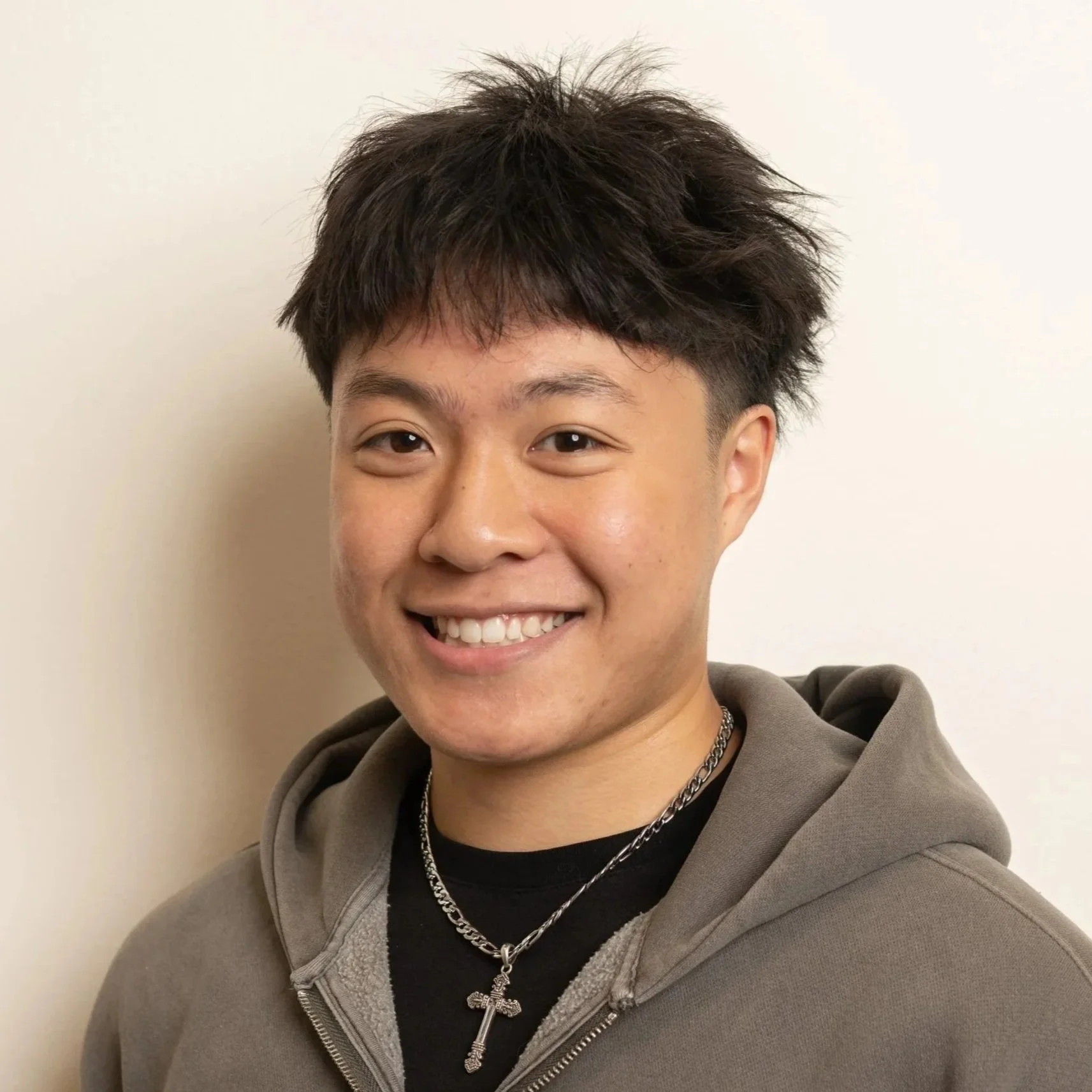 Male staff member with short hair smiling in white shirt on plain background.