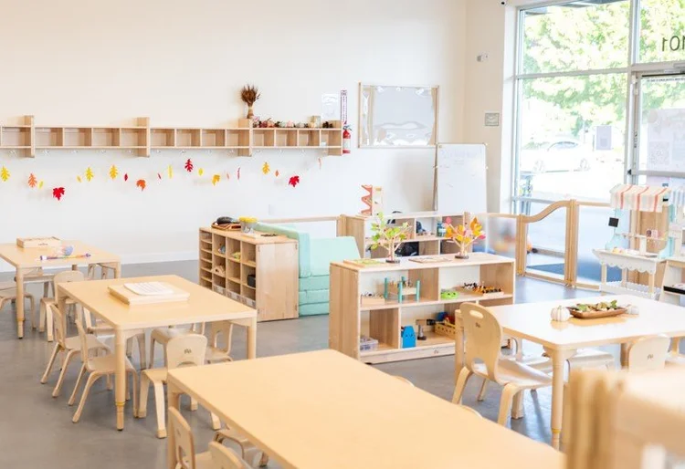A light-filled Cherubs classroom with low wooden shelves and child-sized tables.