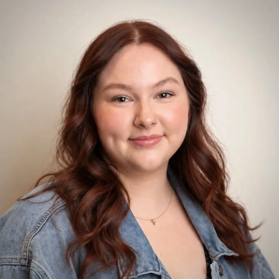 Friendly Cherubs team member in sweater and necklace, softly smiling on white background