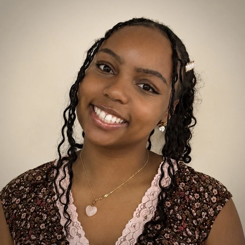Cherubs teacher with braided hair and pearls smiling for staff photo on plain background.