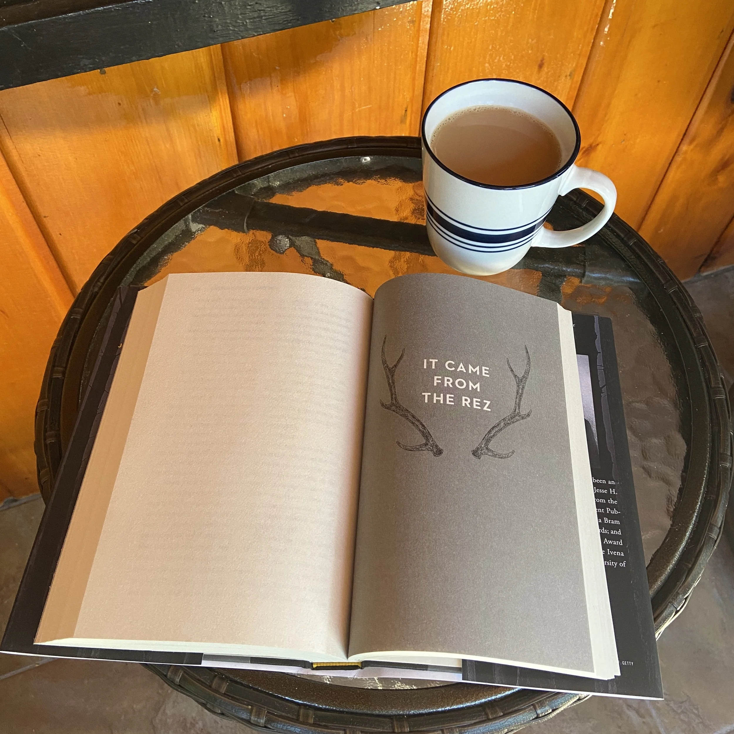 Cup of coffee and book open to a page that reads IT CAME FROM THE REZ