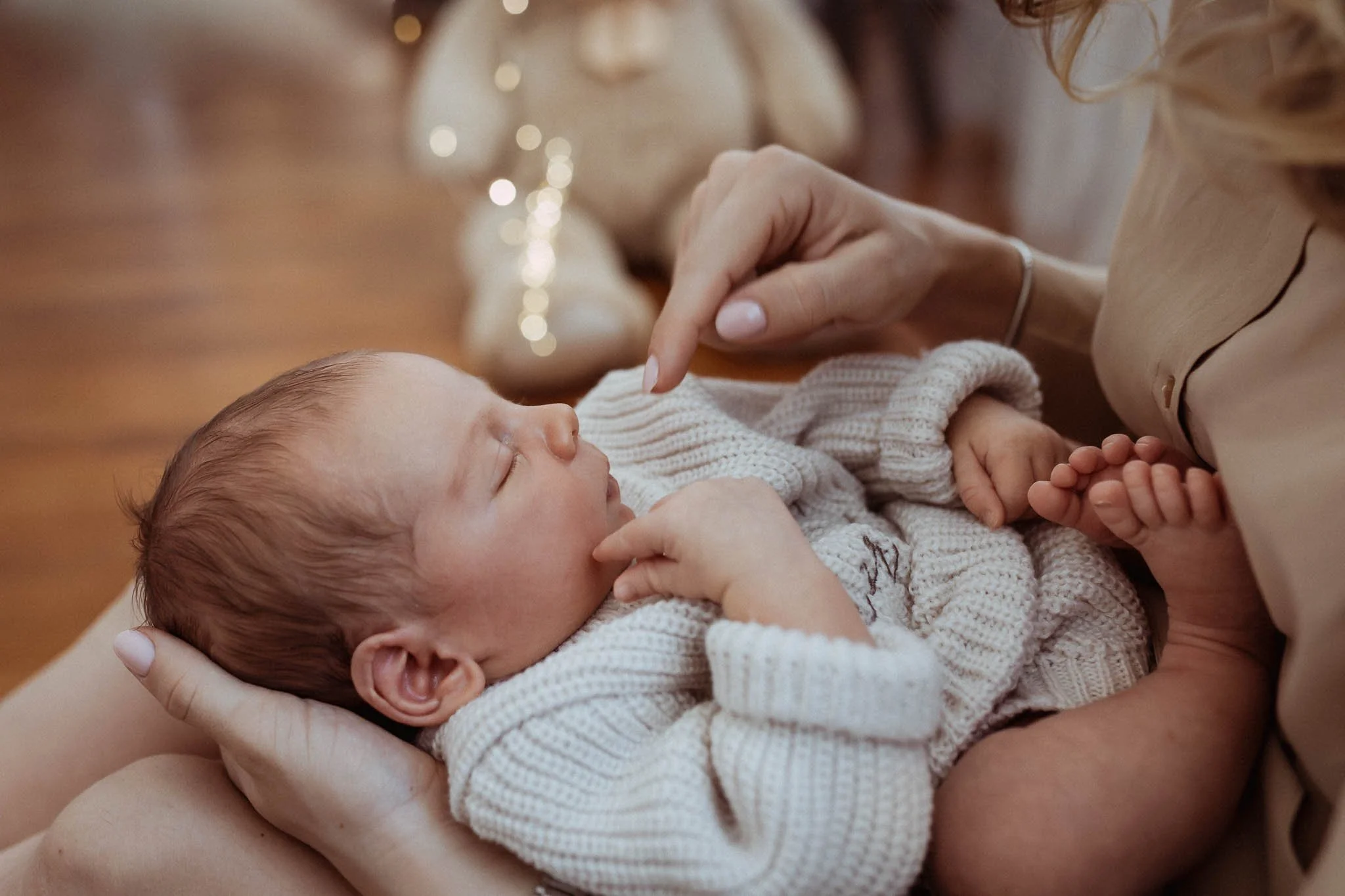 A newborn baby cradled in an adult's hands against a dark background.