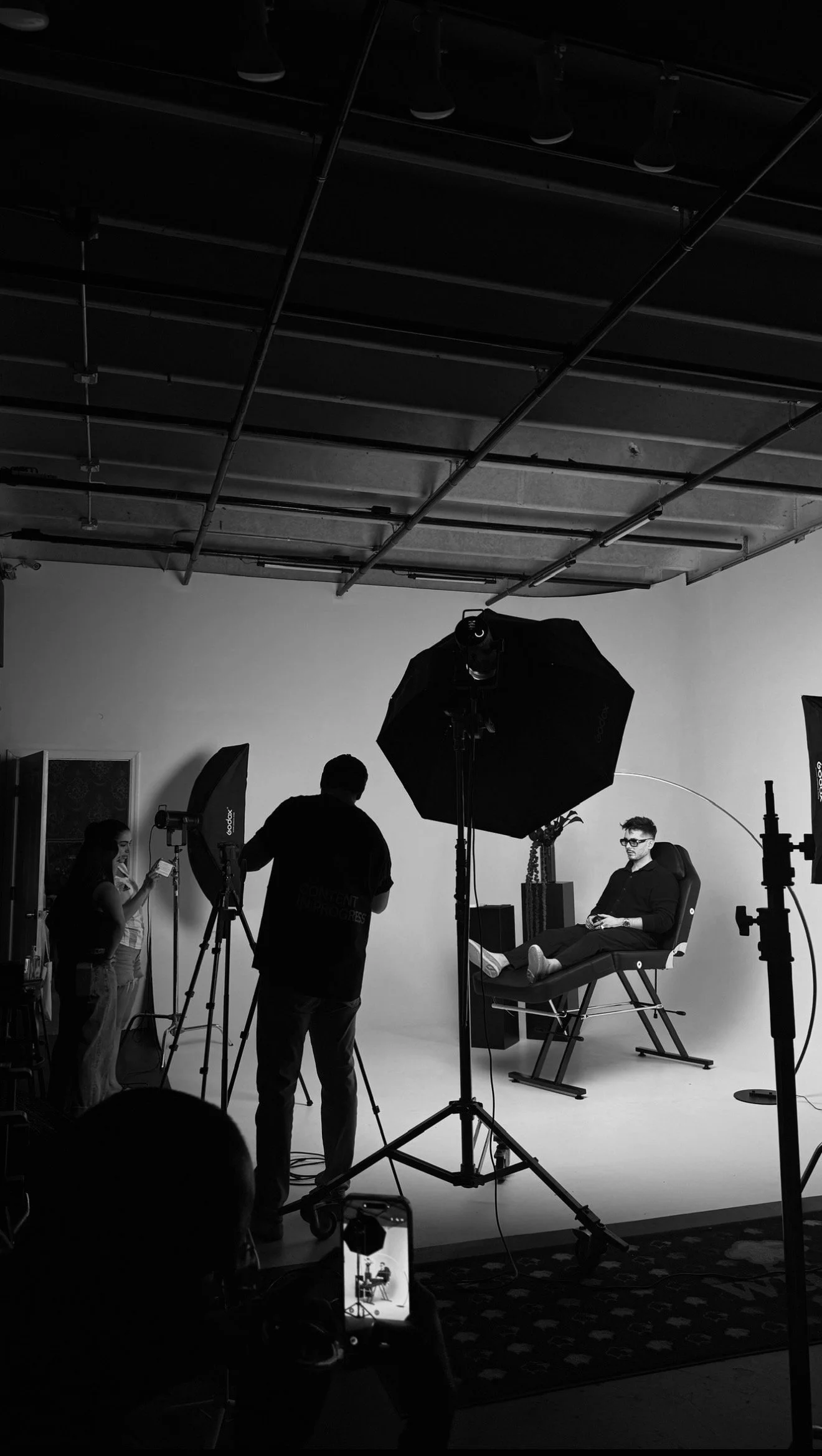 Photography studio with lighting equipment and a large white backdrop, black curtains on the sides, and workspace marked on the floor.