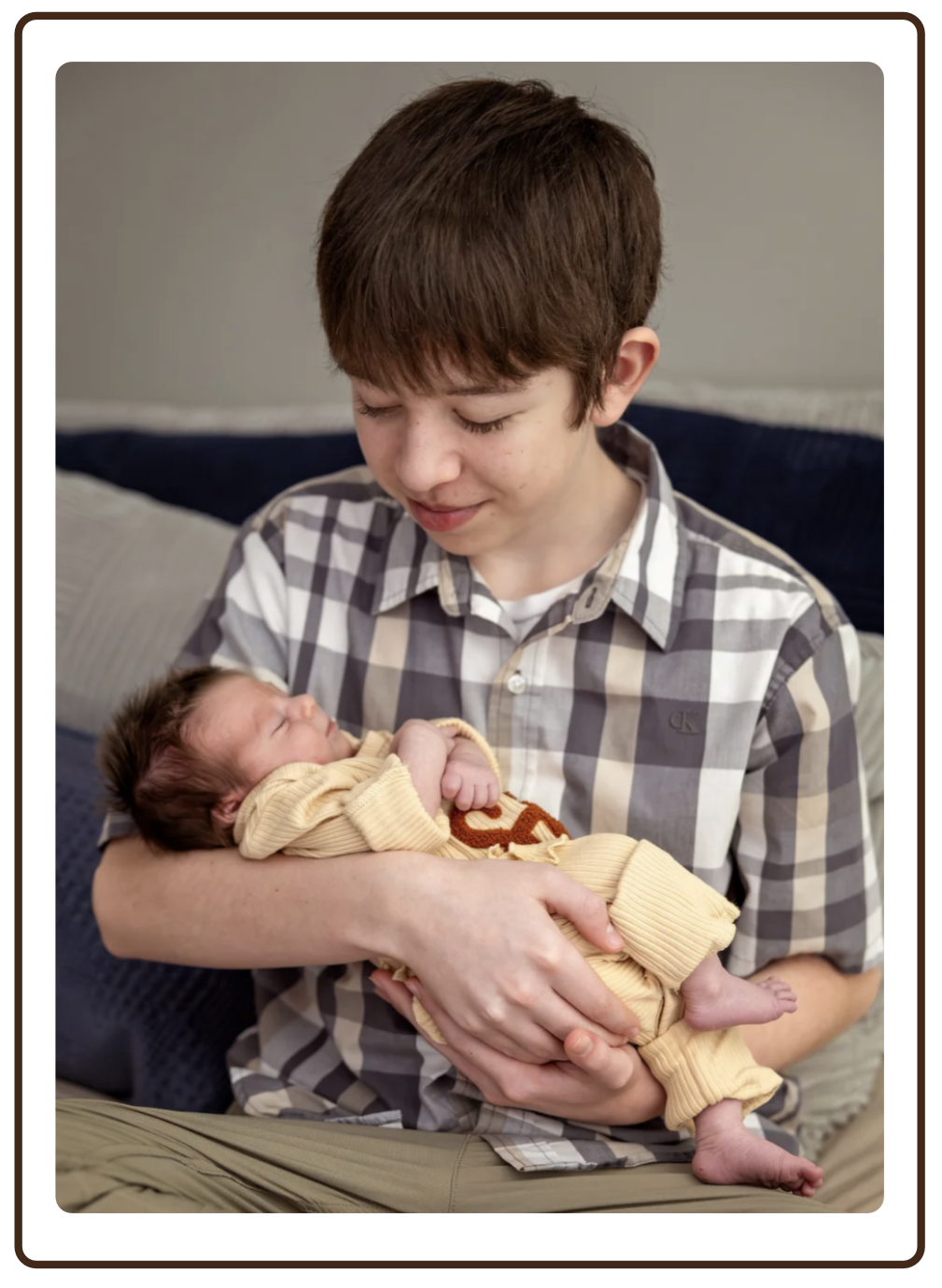 A boy holding a newborn baby wrapped in a yellow blanket.