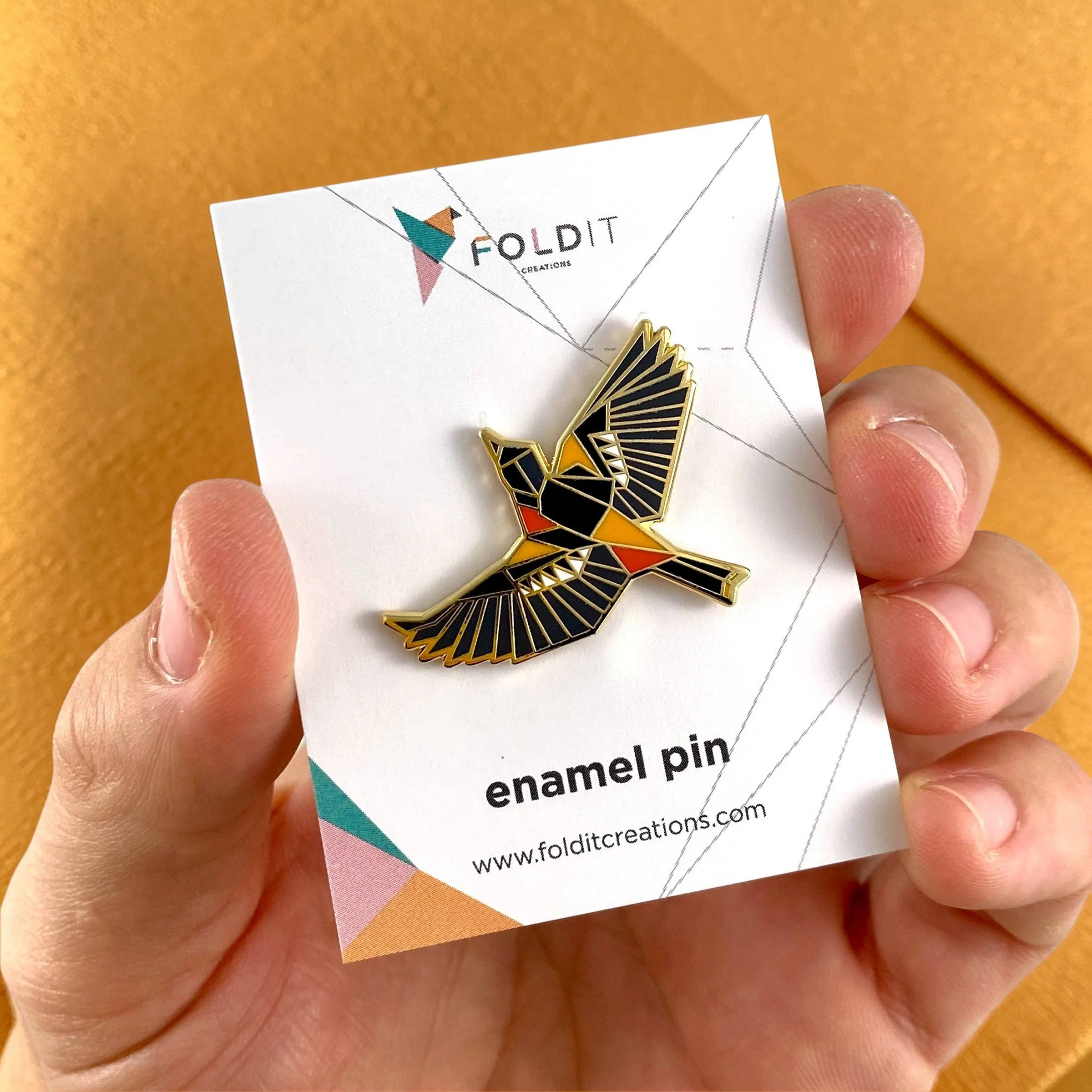 Baltimore Oriole enamel pin – a unique bird themed gift for bird lovers and backyard bird watchers. Hard enamel pin with secure double pin backing and original FoldIT Creations design.