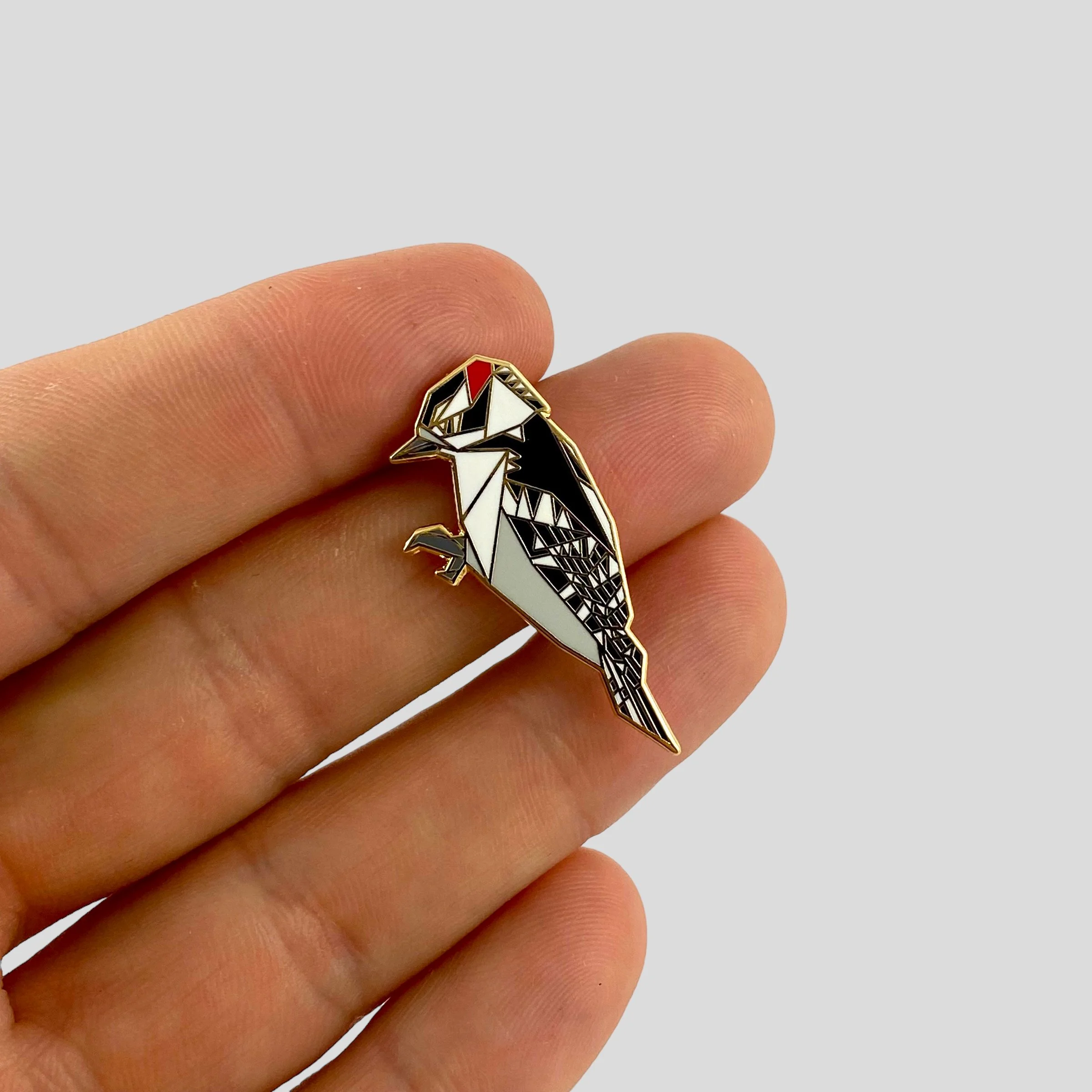 Origami downy woodpecker enamel pin – a unique bird themed gift for bird lovers and bird watchers. Hard enamel pin with secure double pin backing and original FoldIT Creations design