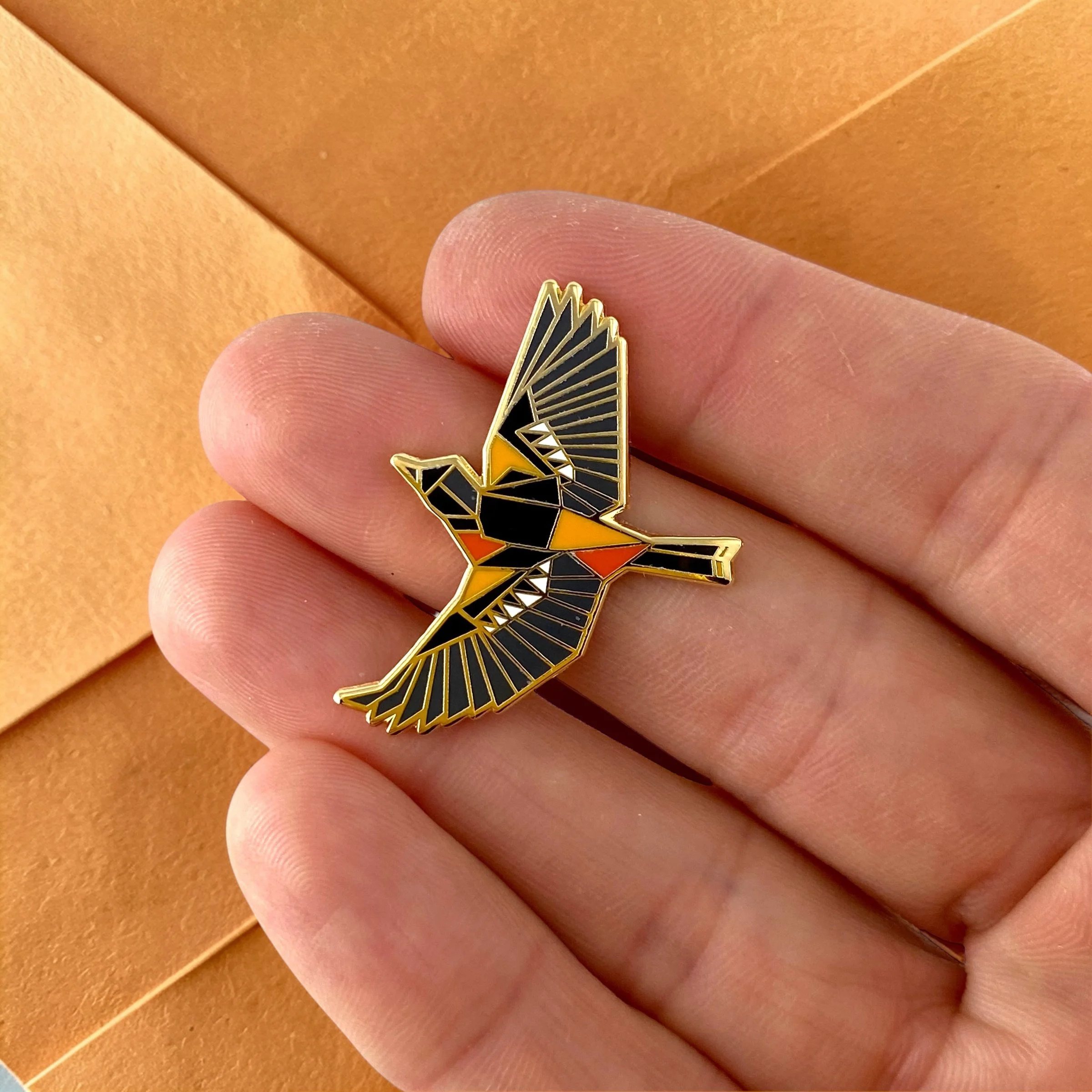 Baltimore Oriole enamel pin – a unique bird themed gift for bird lovers and backyard bird watchers. Hard enamel pin with secure double pin backing and original FoldIT Creations design.