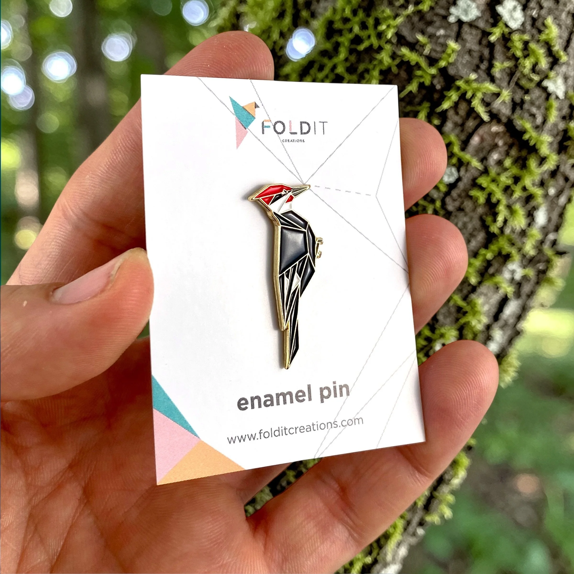 Origami pileated woodpecker enamel pin – a unique bird themed gift for bird lovers and bird watchers. Soft enamel pin with secure double pin backing and original FoldIT Creations design.